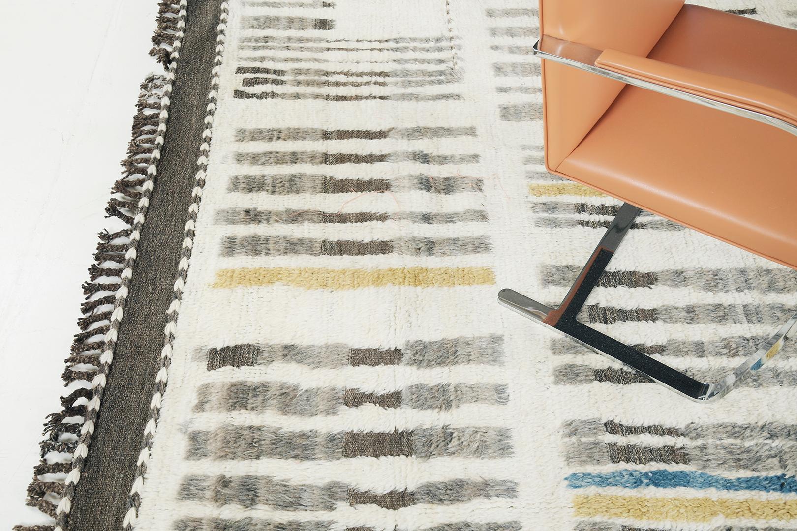 Handwoven of wool, 'Baccata' uses line work and colour to create definition and movement. Line detailing in gray, gold and cobalt blue fascinatingly move across the rug. Detailed natural flat weave runs around the border with tassels adding an