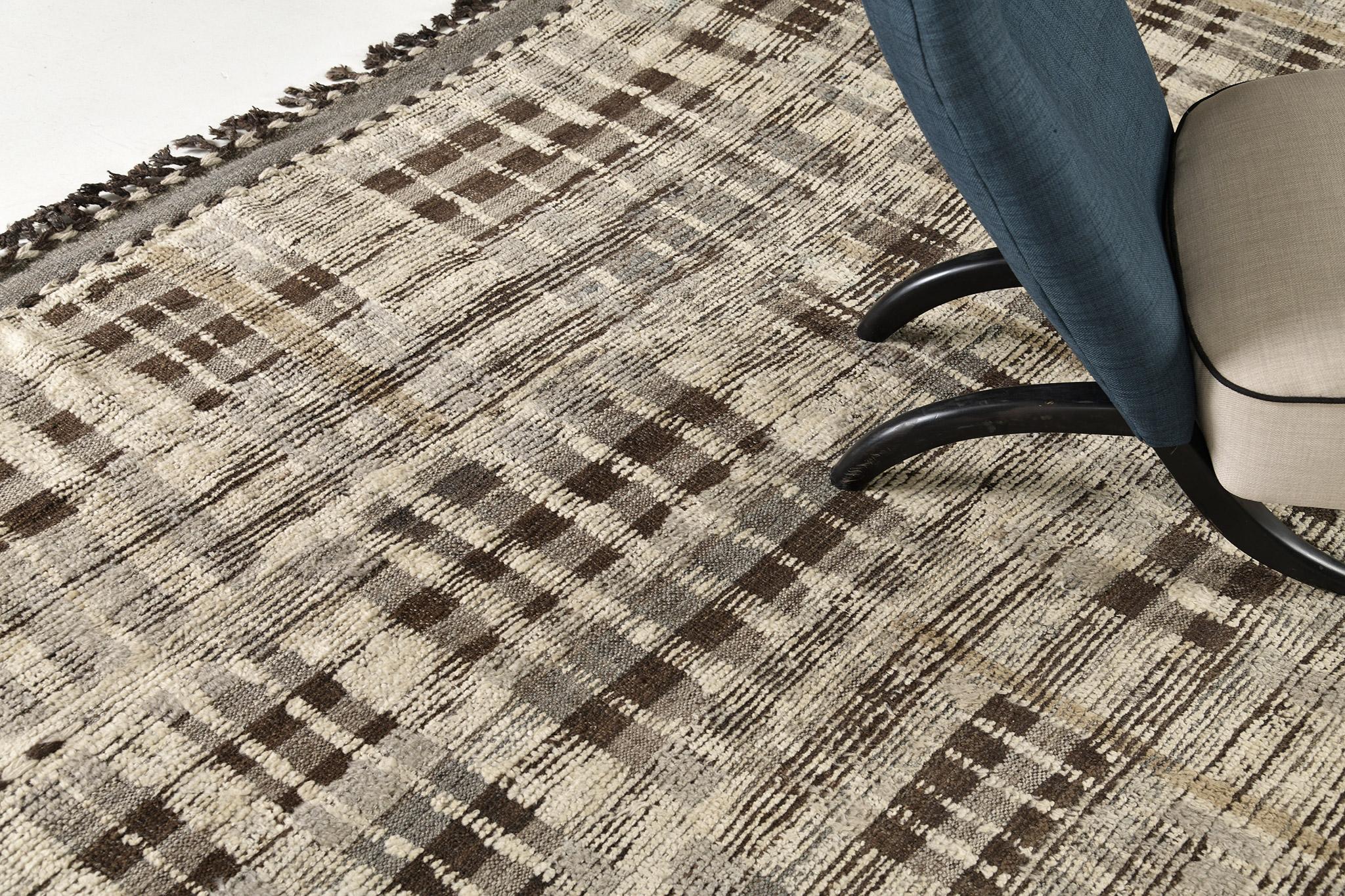 Baccata verwendet Linienführung und Farbe, um der handgewebten Wolle Definition und Bewegung zu verleihen. Liniendetails in Khaki und Umbrabraun ziehen sich faszinierend über den Teppich. Ein detailliertes, natürliches Flachgewebe verläuft um den