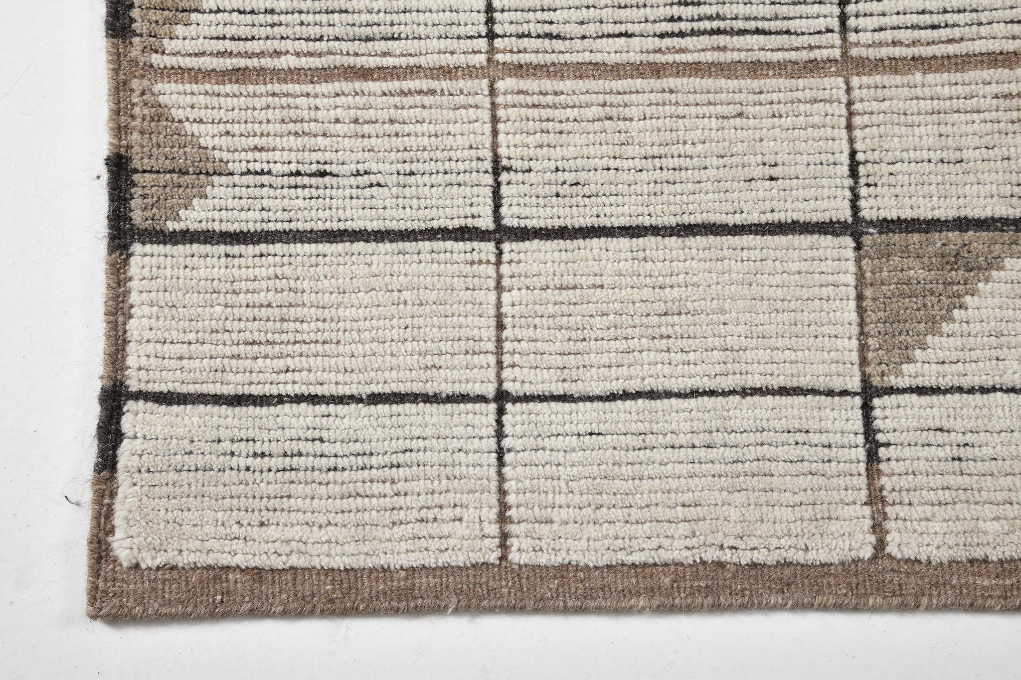 Le tapis 'Bouchet' de la collection Estancia présente des grilles rectangulaires qui courent tout le long de ce tapis époustouflant. Rendu dans les tons terreux de l'écru, du charbon et du camel, il présente des losanges en forme de puzzle qui