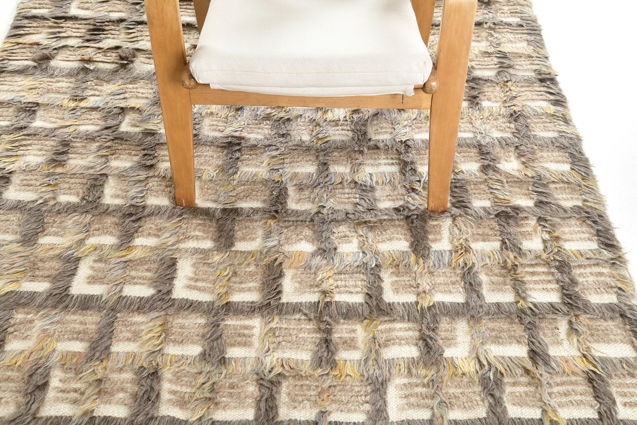 The Hanin rug is a complex multi-toned grid motif in long pile lines with shapes of trim pile, and open flatweave accents. Texturally rich with tonal dimensional effects, Hanin is rendered in a warm mix of cacao, clay and gold inflected mixed gray