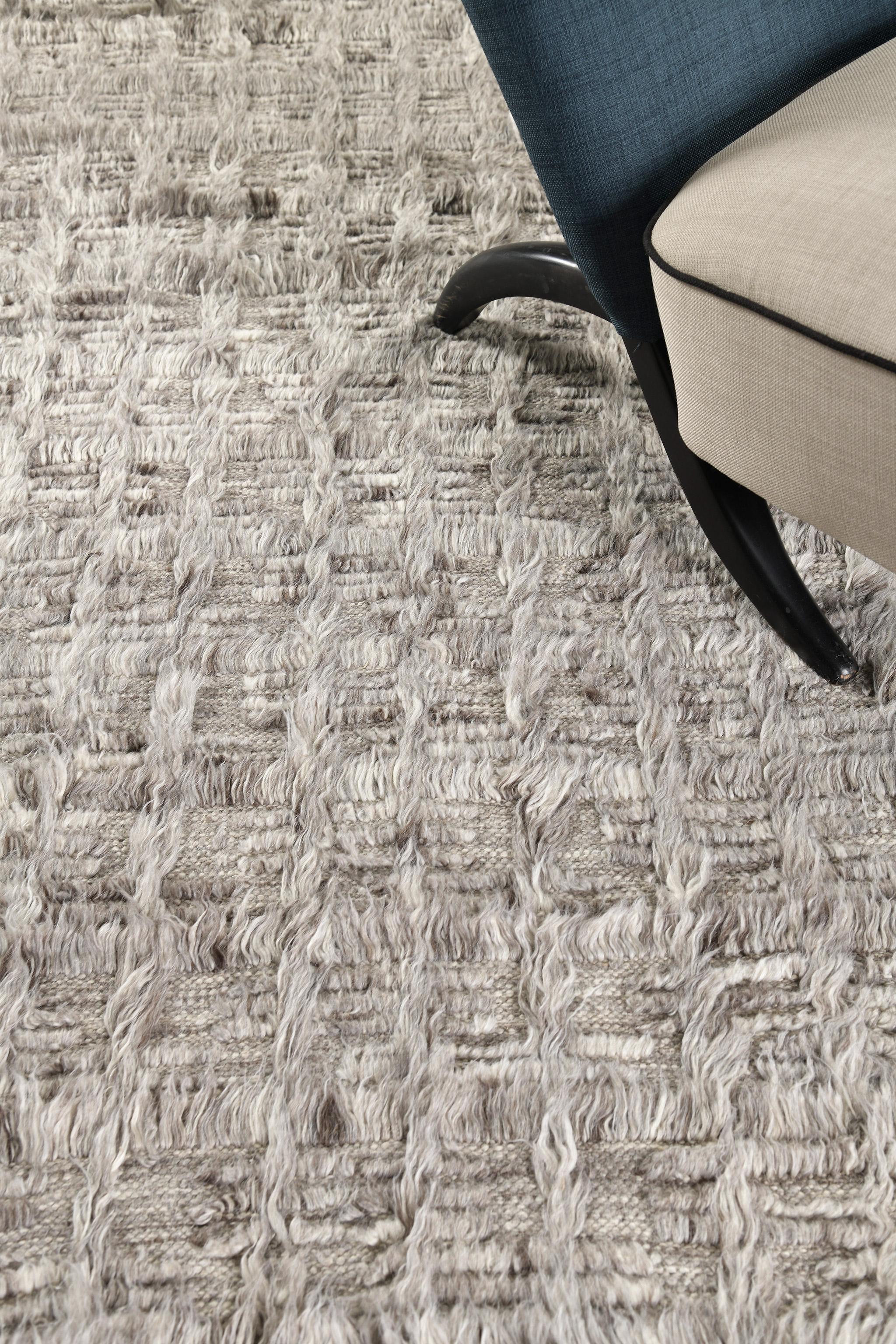 The Mani rug is a monochrome design syncopating long and short pile with open flatweave. This piece is made in tones of cool heathered gray.

An extension of Mehraban’s popular Amihan design, the Sahara Collection delves further with grid-riffs of