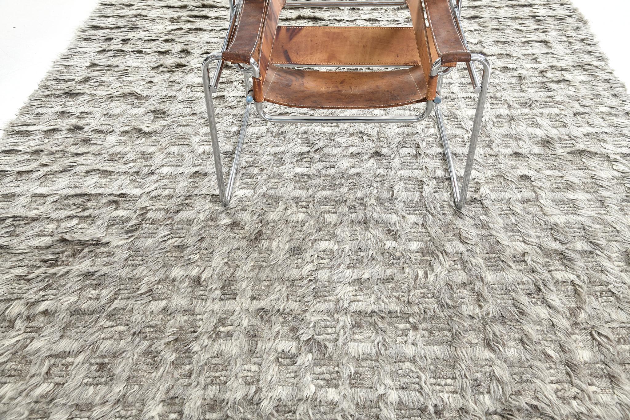 Der Teppich Mani ist ein monochromes Design, bei dem sich Lang- und Kurzflor mit offenem Flachgewebe abwechseln. Dieses Stück ist in kühlen Grautönen gehalten.

Die Sahara Collection'S ist eine Erweiterung des beliebten Amihan-Designs von Mehraban