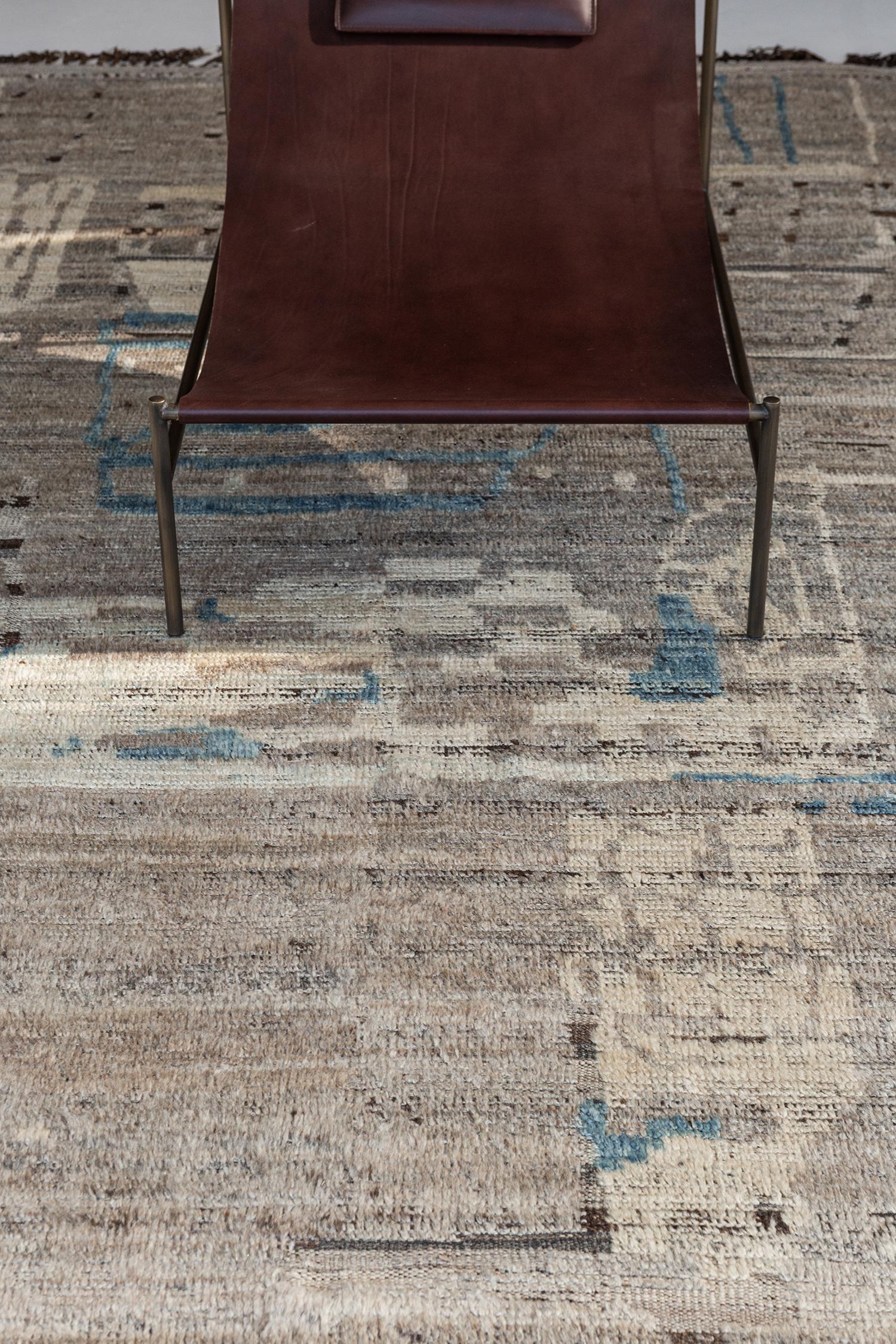 Meliska' is a captivating textured rug with irregular motifs inspired from the Atlas Mountains of Morocco. Earthy tones of ivory, taupe, cerulean blue and chocolate brown surrounded by umber brown shag work cohesively to make for a great