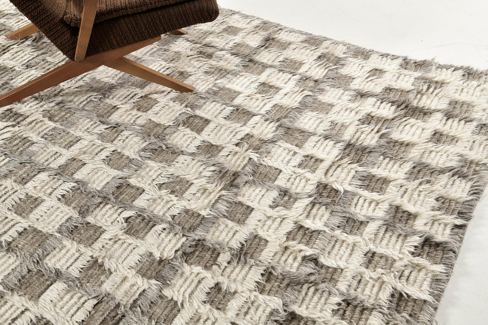 The Miha rug features a checkerboard motif interplaying shifted tonal grid lines in a multi-pile design. This piece is rendered in ivory with cool and khaki greys. 

An extension of Mehraban’s popular Amihan design, the Sahara Collection delves
