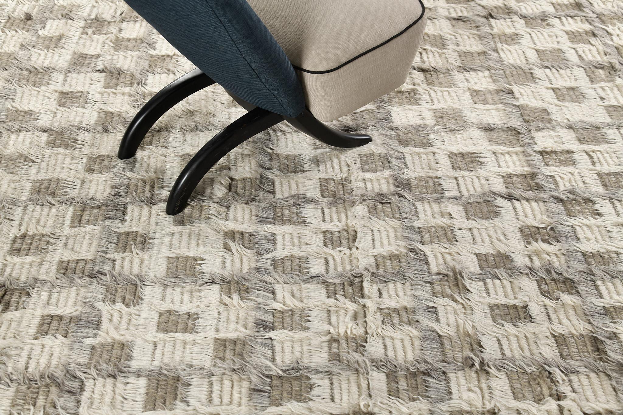 The Miha rug features a checkerboard motif interplaying shifted tonal grid lines in a multi-pile design. This piece is rendered in ivory with cool and khaki grays. 

An extension of Mehraban’s popular Amihan design, the Sahara Collection delves