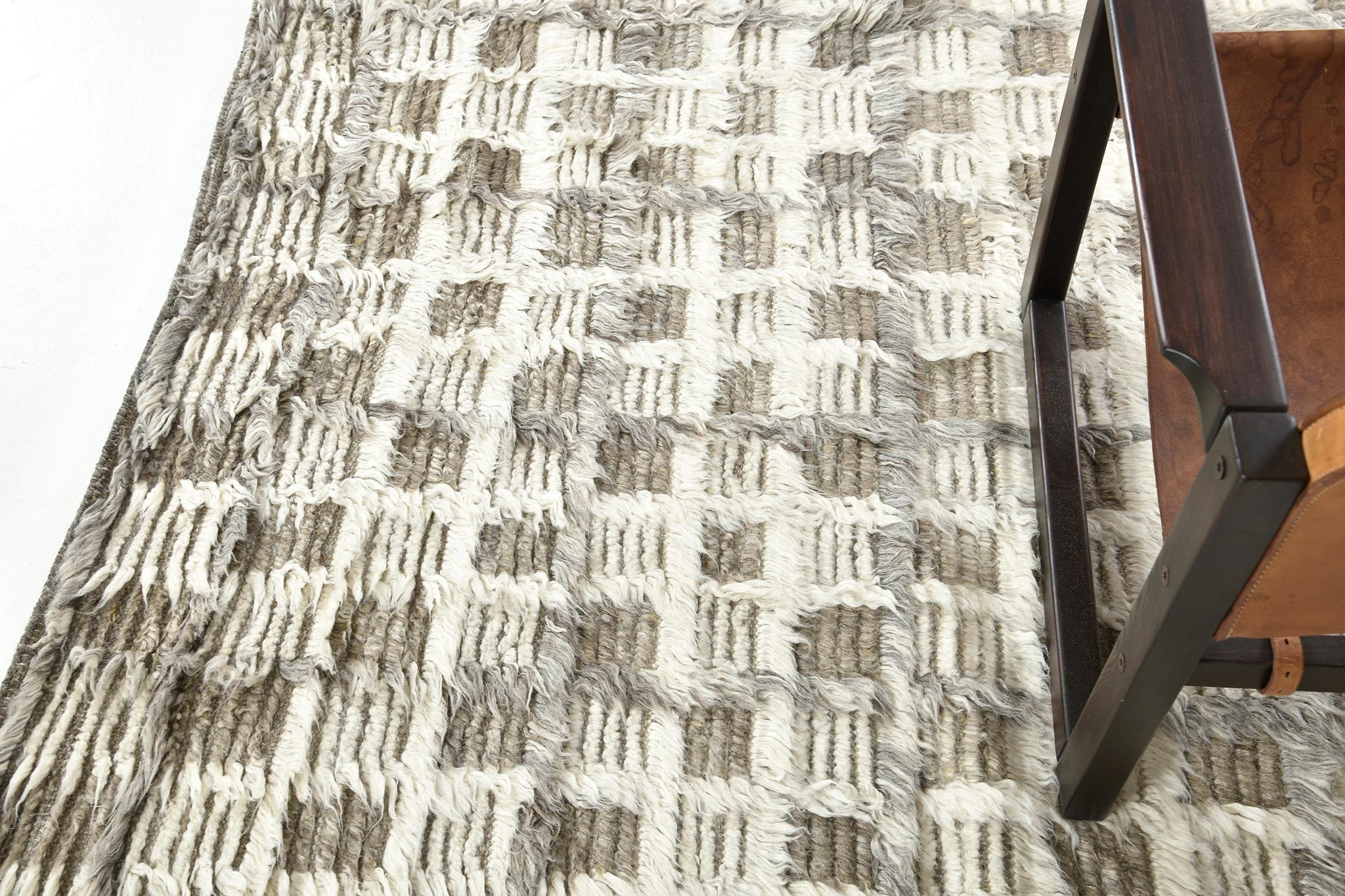The Miha rug features a checkerboard motif interplaying shifted tonal grid lines in a multi-pile design. This piece is rendered in ivory with cool and khaki grays.

An extension of Mehraban’s popular Amihan design, the Sahara Collection delves