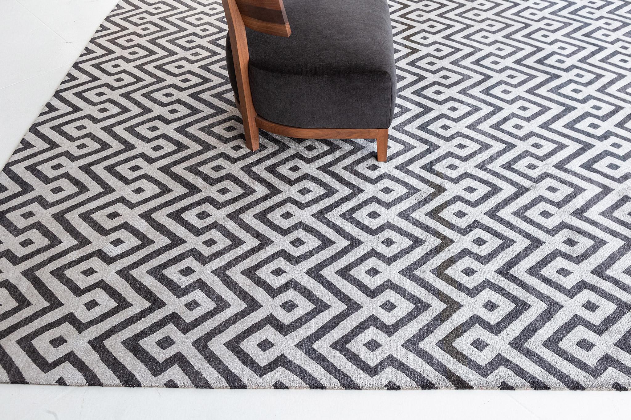 Devi' is a modern design weaving traditional geometric motifs in a modern day lattice pattern. Fascinating black and gray pattern run over along the magnificent composition of this masterpiece. This eye-catching rug will definitely elevate and bring