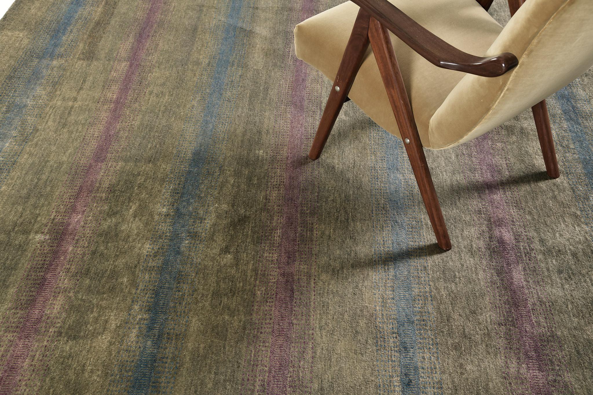 Noel is luxurious wool that features alternating red and blue lines over the gradient of variegated tones of olive and black. This rug is easy to harmonize with a variety of interiors. A timeless design that will be adored and treasured by the next