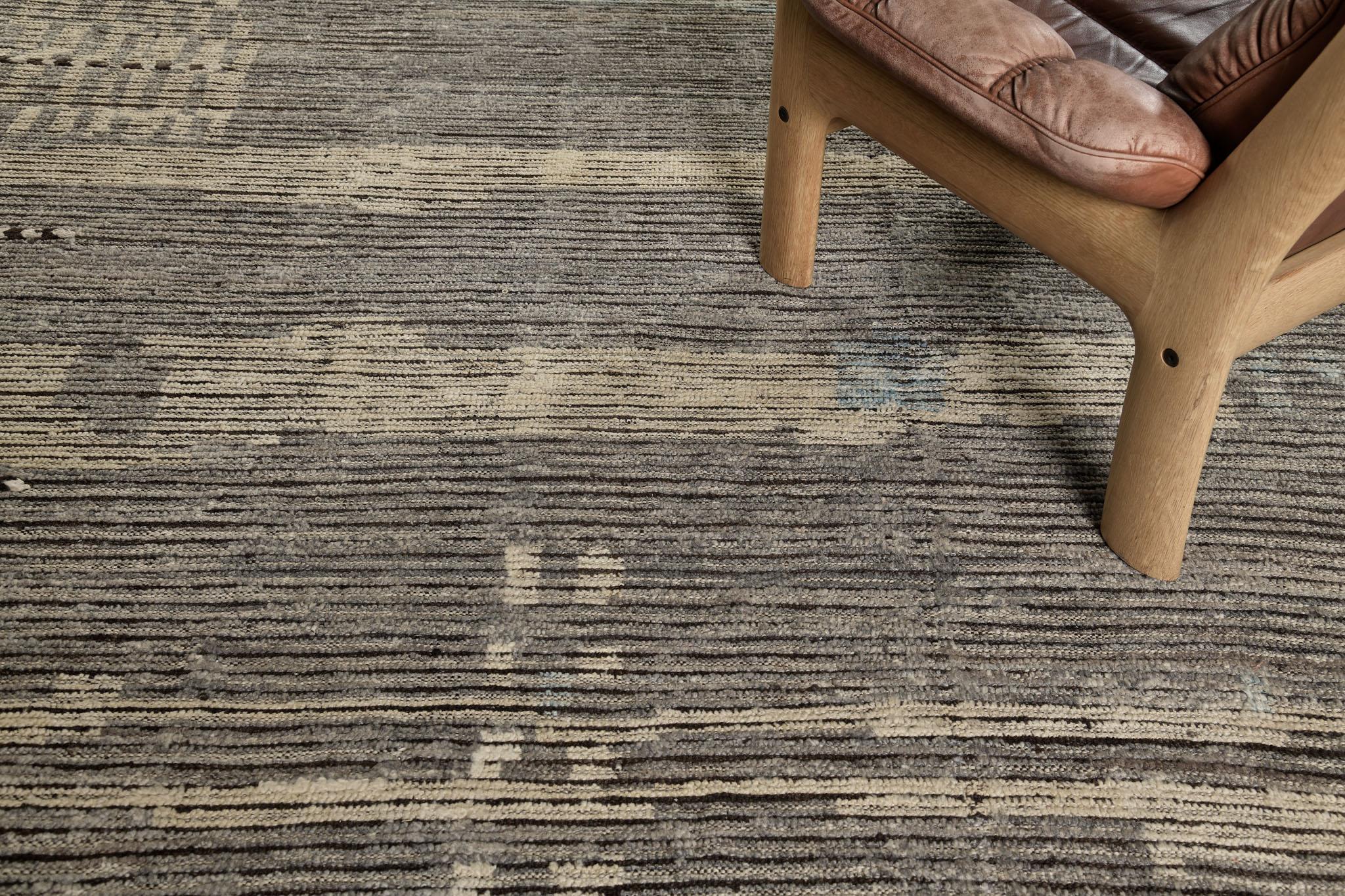 Nakhla is a natural earth-toned rug and a modern interpretation of the Moroccan world. These rugs' irregular patches and linear strokes of cream, blue, and gray resemble the fibers of nature and their ability to be used for crafts such as cords and