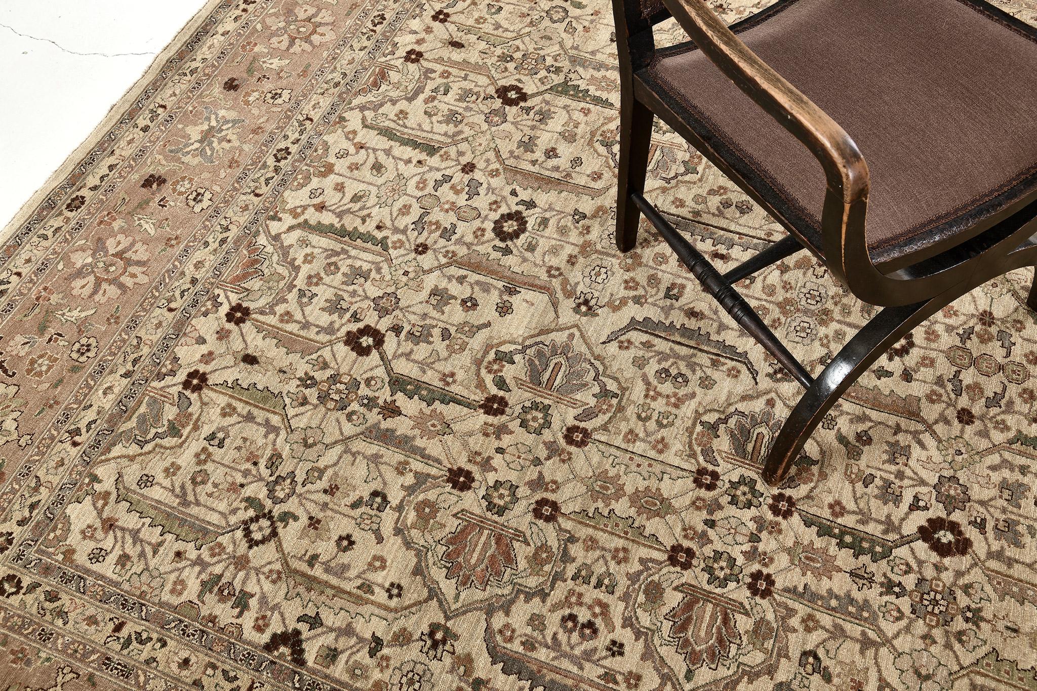 Un tapis sophistiqué de conception Tabriz qui présente les tons chauds de l'ivoire, de l'or, du rose cannelle et du sable dans la palette de couleurs terreuses la plus recherchée. Les motifs botaniques majestueux de brins de fleurs, de palmettes