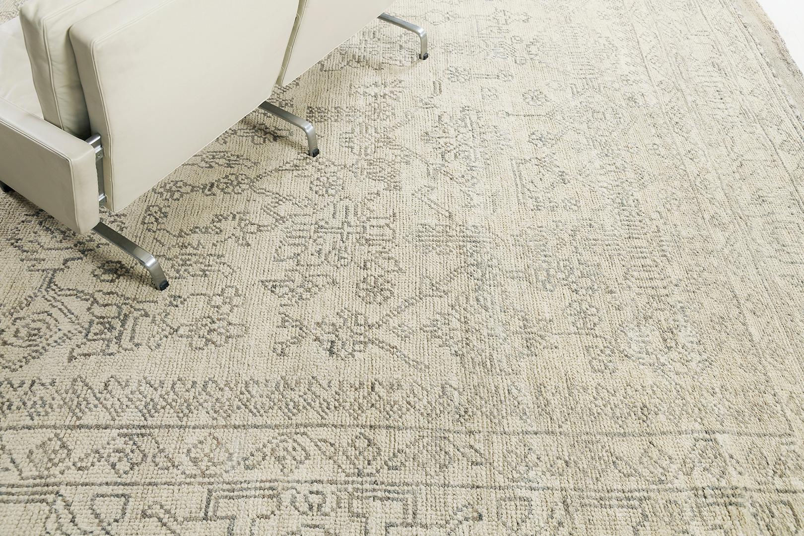 Ein stilvoller Oushak-Revival-Teppich in den kühlen Tönen von Lehm und Holzkohle, anmutig stilisiert mit majestätischen botanischen Details. Dieser klassische und zierliche Teppich aus handgesponnener Wolle wird von einer ergänzenden Bordüre