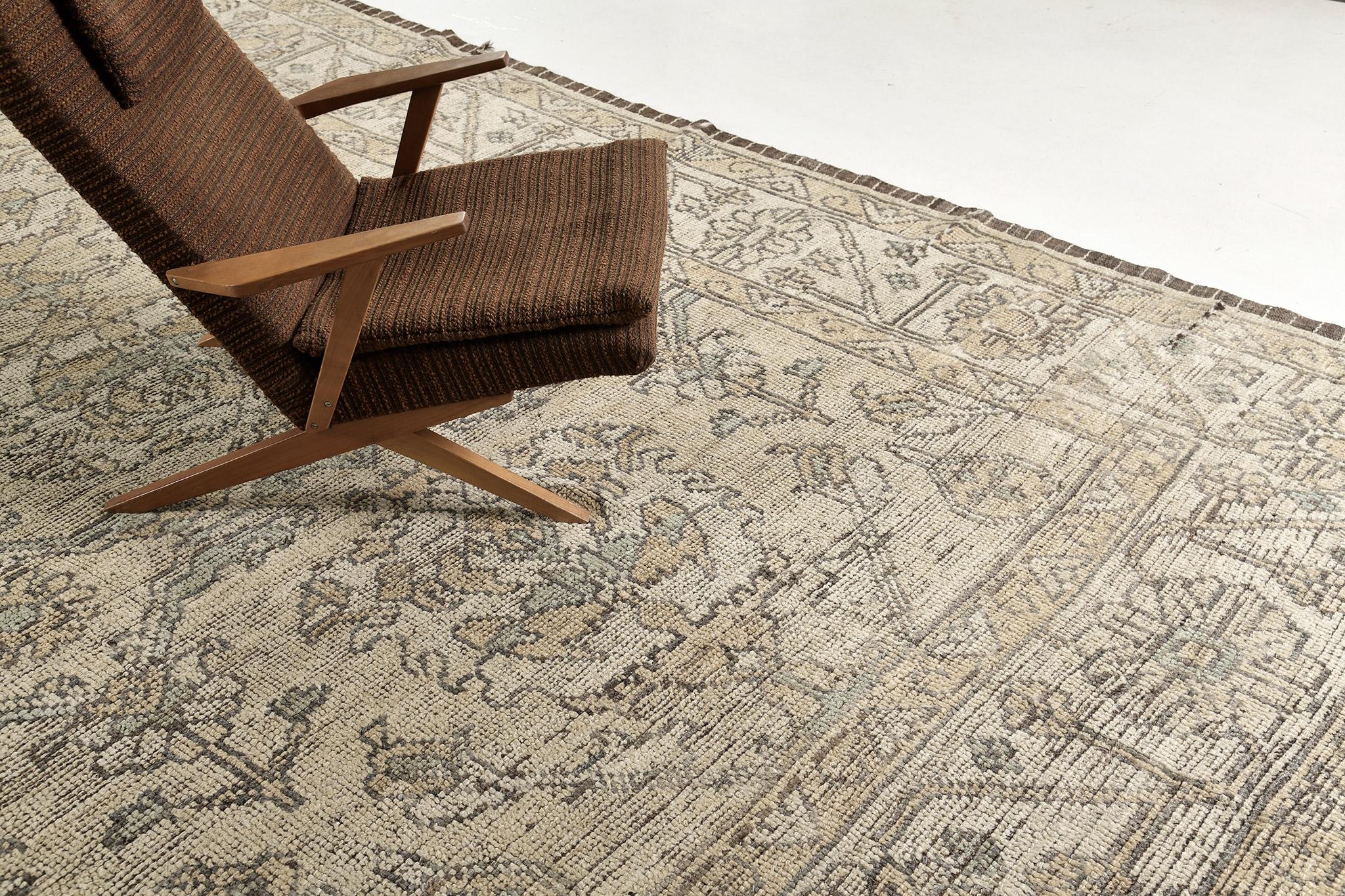 An alluring Oushak design revival rug that has an intricate and timeless pattern. Featuring the collaboration of muted tones of hazel wood and cream, this bewildering rug is composed with enchanting graceful florid elements that create a symmetrical