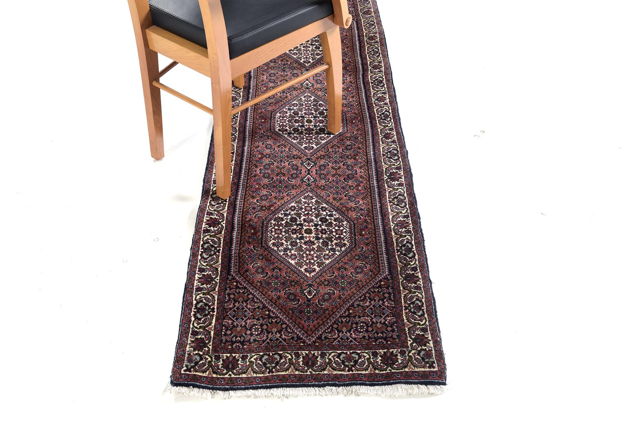 A sophisticated Persian Bidjar Runner that features three hexagonal lozenge medallions composed of symmetrical botanical elements in the majestic and regal tones of rust and ivory. This refined rug charms with ease and beautifully embodies dainty
