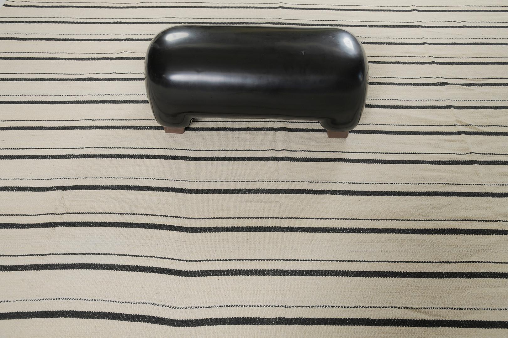 Dieser persische Jejim-Kilim ist flach gewebt und zeigt ein vielseitiges Muster aus schwarzen, mehrfarbigen Streifen in einem neutralen Wollton. Er eignet sich perfekt für moderne, zeitgenössische Innenräume. Die grafischen Streifen auf dem Teppich