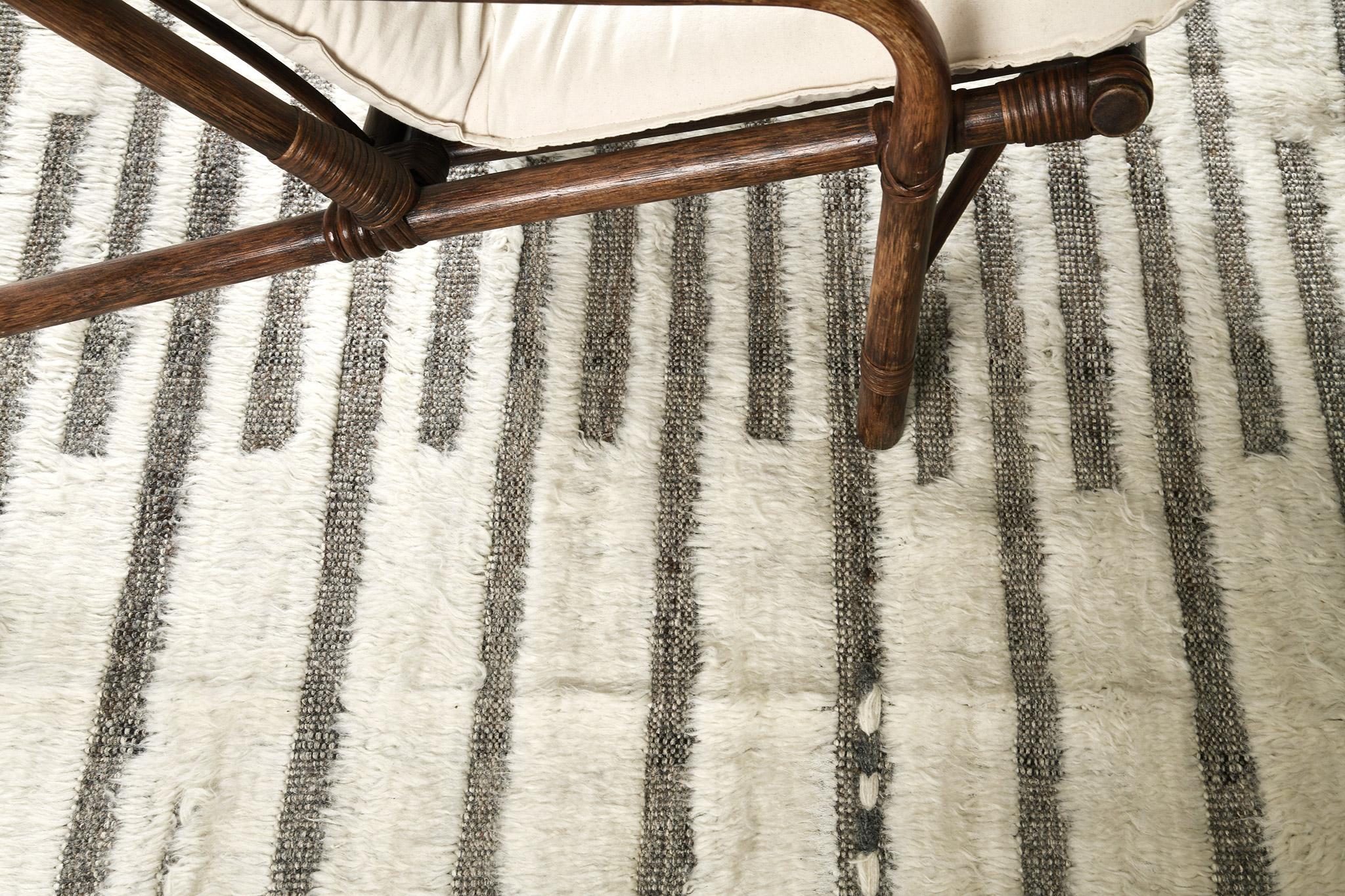 Handwoven of wool, Rashabar uses line work and color to create definition and movement. Embossed detailing of taupish grey moves across the rug with an umber brown shag surface. Natural flat weave runs around the border with tasseled ends.

Rug
