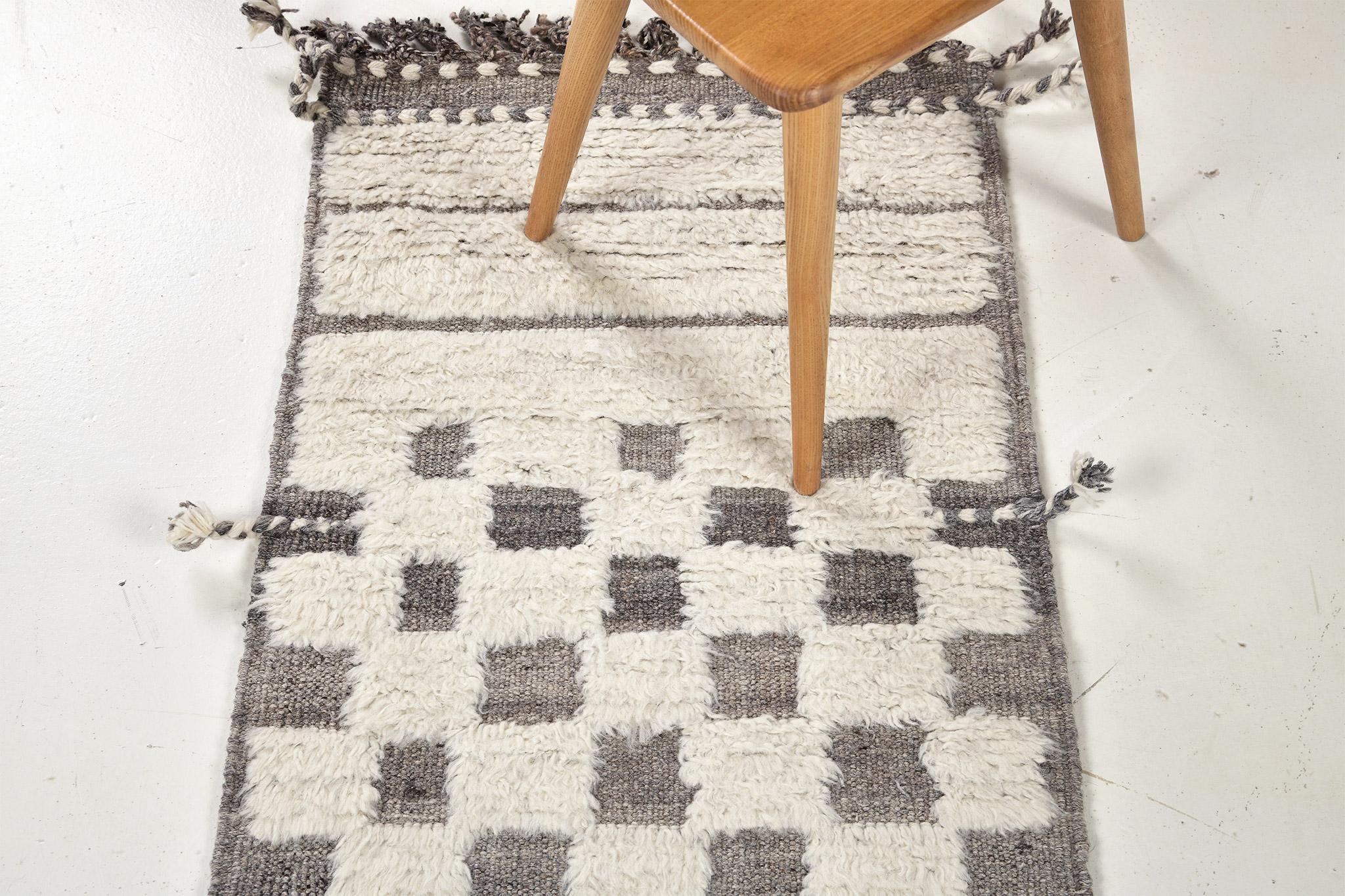Sirocco' is a stunning hand woven gray rug with embossed detailing in a checkered pattern atop a natural ivory pile weave. Beautiful tassels and bordered designs add a timely and one of a kind essence for the modern design world. Haute Bohemian