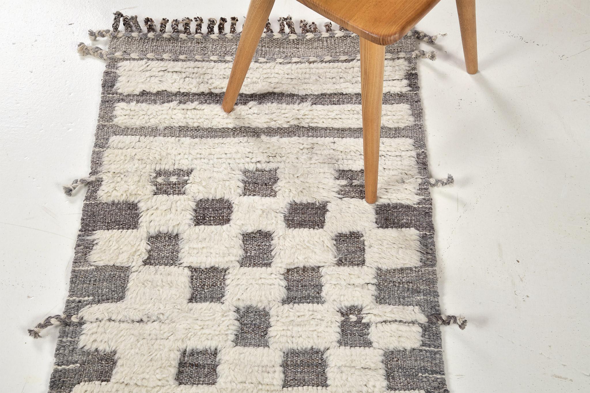 Sirocco' is a stunning hand woven gray rug with embossed detailing in a checkered pattern atop a natural ivory pile weave. Beautiful tassels and bordered designs add a timely and one of a kind essence for the modern design world. Haute Bohemian