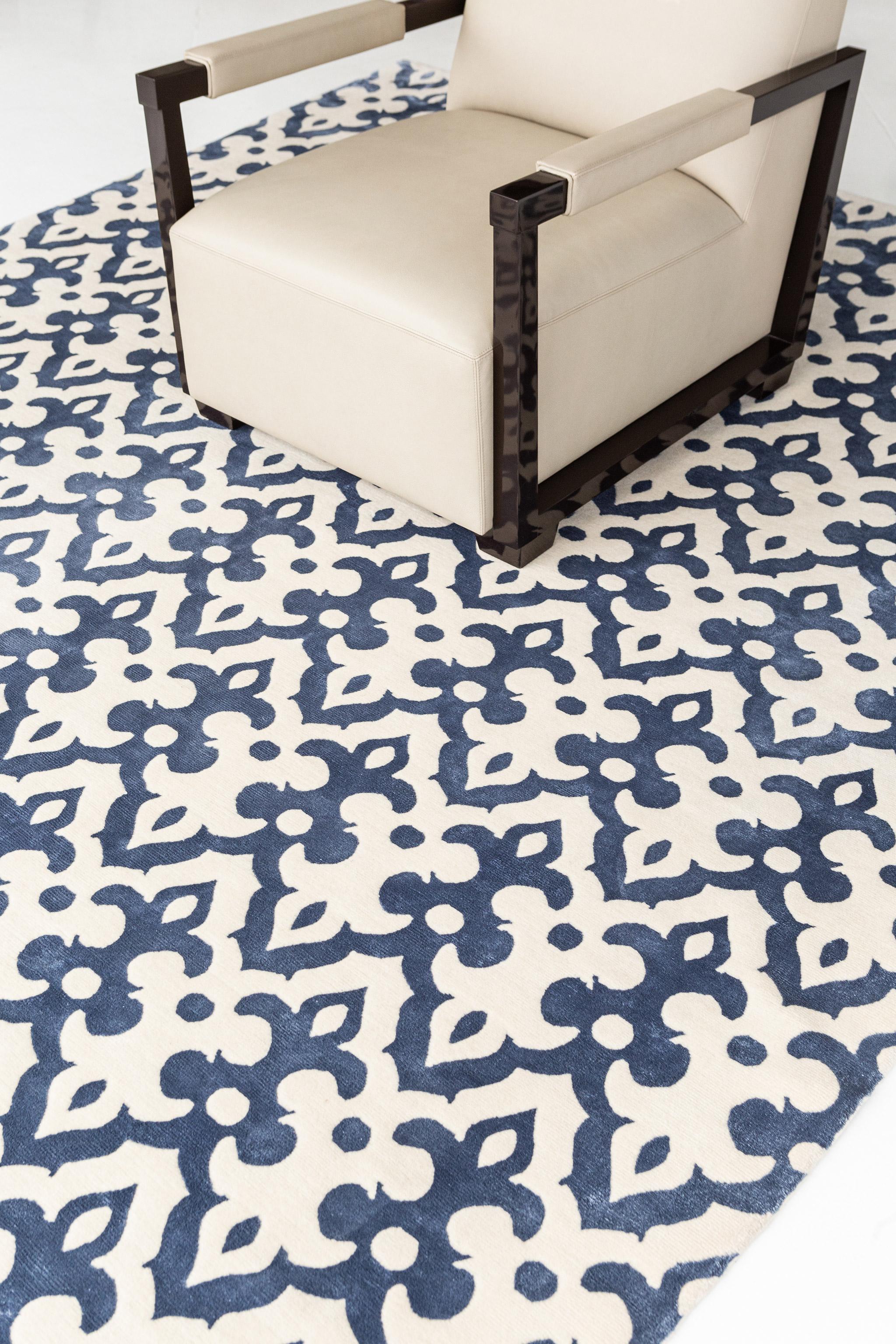 Dieser Transitional Design-Teppich Moresco' ist raffiniert und subtil, ohne auf Eleganz zu verzichten. Es weist ein sich allover wiederholendes, verziertes Muster auf, das auf einem indigoblauen Feld liegt. Mit seiner subtilen und luftigen