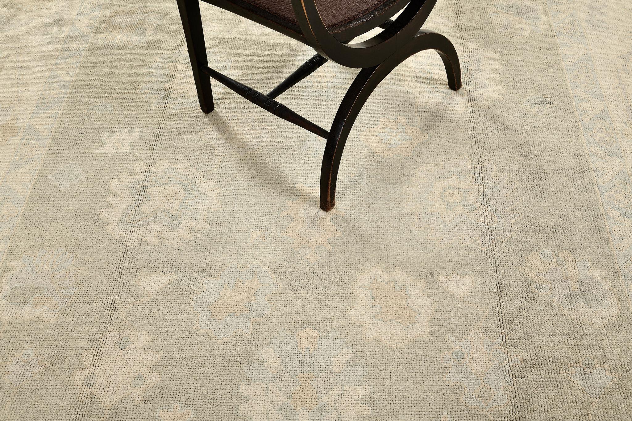 Durch die Verwendung von kühlen, gedeckten Farbtönen strahlt dieser fesselnde Oushak-Teppich eine schlichte Eleganz aus. Kunstvoll aus handgesponnener Wolle gefertigt, trägt es kunstvolle Bordüren aus blühenden Palmetten, gefolgt von einem