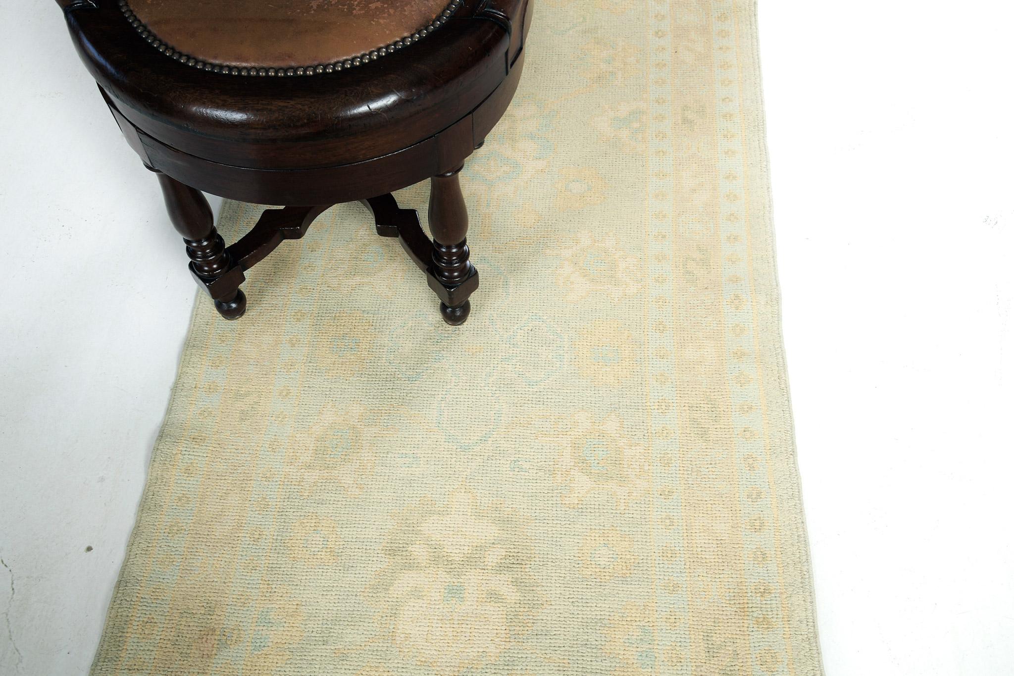 An amazing Turkish Oushak revival rug that has an illustration of a dainty blossoming vibe. Distinctive palmettes, graceful peonies, and connecting twigs are highlighted in elegance in the stunning shades of gold and neutral field and enclosed by a