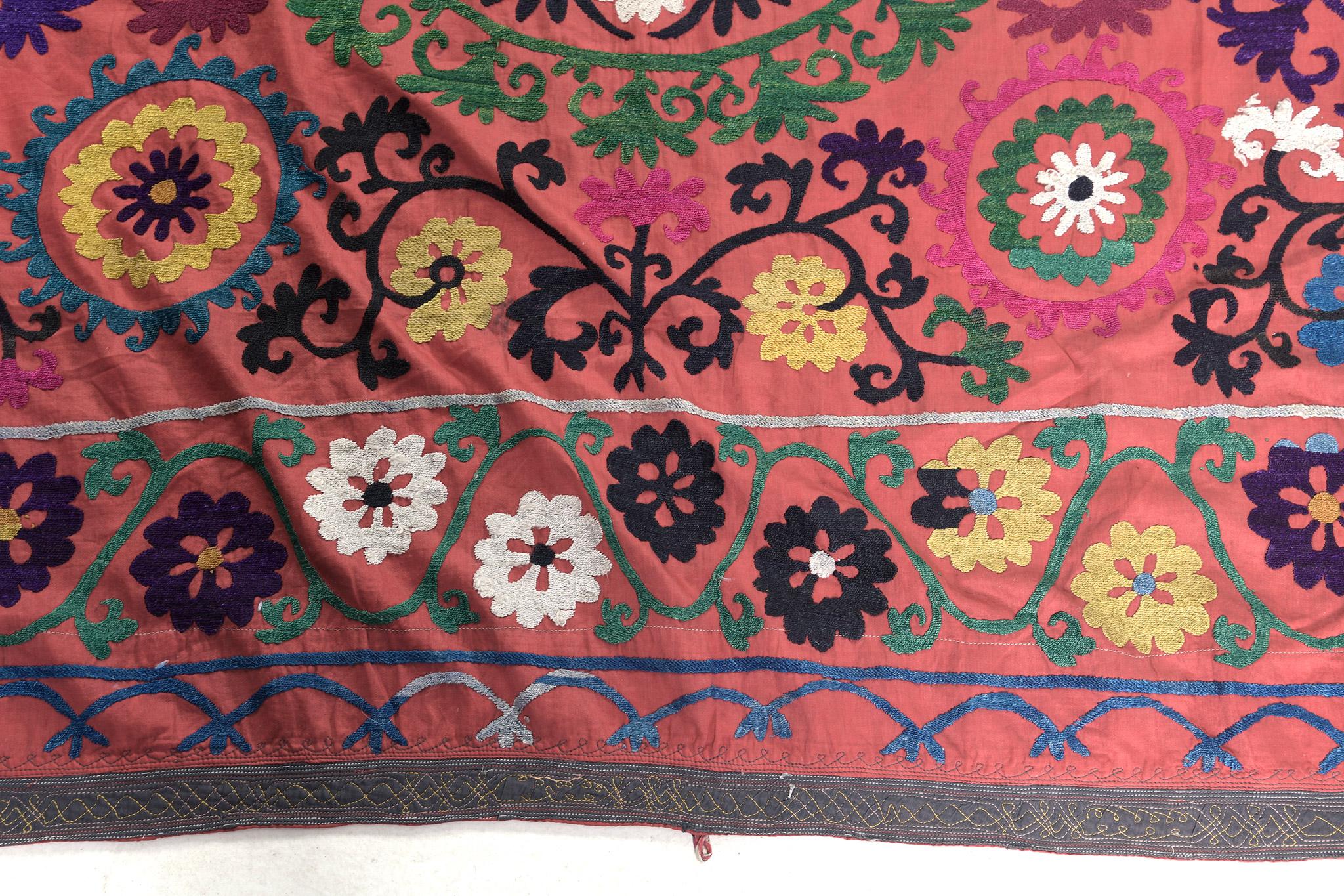 Un vibrant tapis Suzani Vintage Azerbaïdjan Dioxane qui présente une série d'éléments floraux et de vignes qui font ressortir le caractère festif de ce tapis envoûtant. Rendu dans des nuances de couleurs vibrantes et ludiques, ce tapis ajoutera