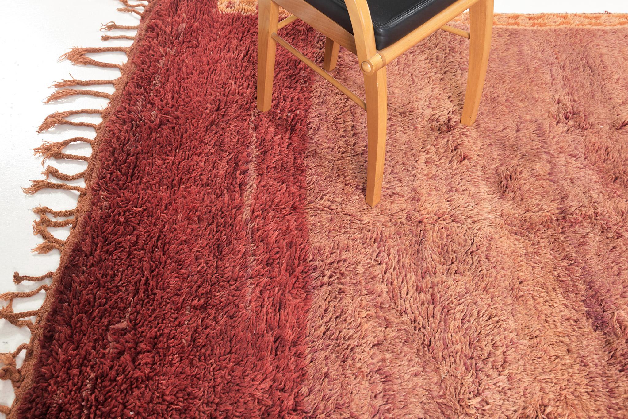 An interplay of stunning gradient colours in this Vintage Moroccan Beni M’Guild Tribe rug that has embossed ornate elements featuring the vibrant gradient shades of fire brick to rust. It vividly displays a plush texture that forms the eclectic