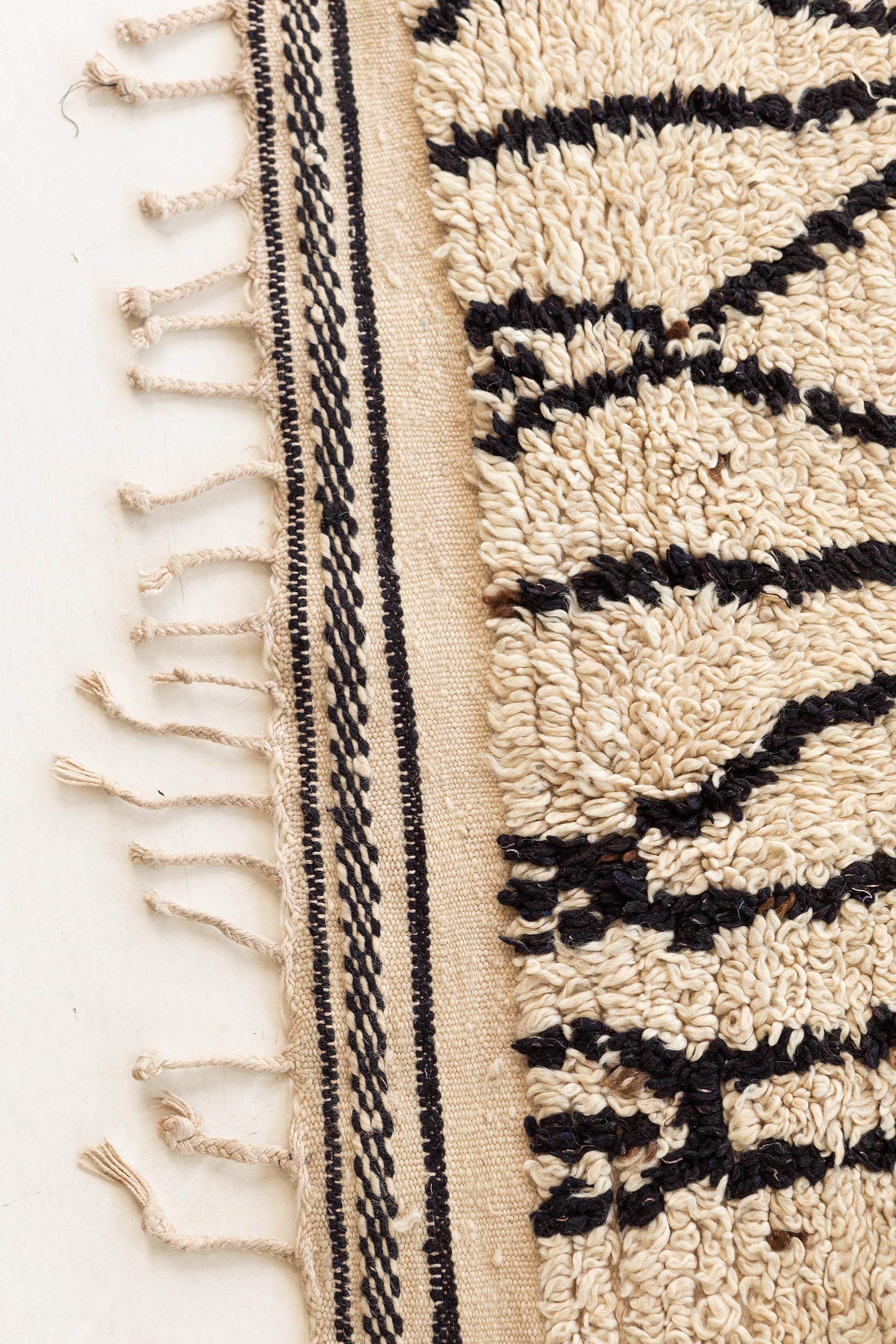 A captivating Vintage Moroccan Azilal Tribe rug that features a variety of elaborate ambiguous motifs all over the cream field emanating its tribal feel. Berber Moroccan rugs are known for the symbolism that is so intricately woven throughout the