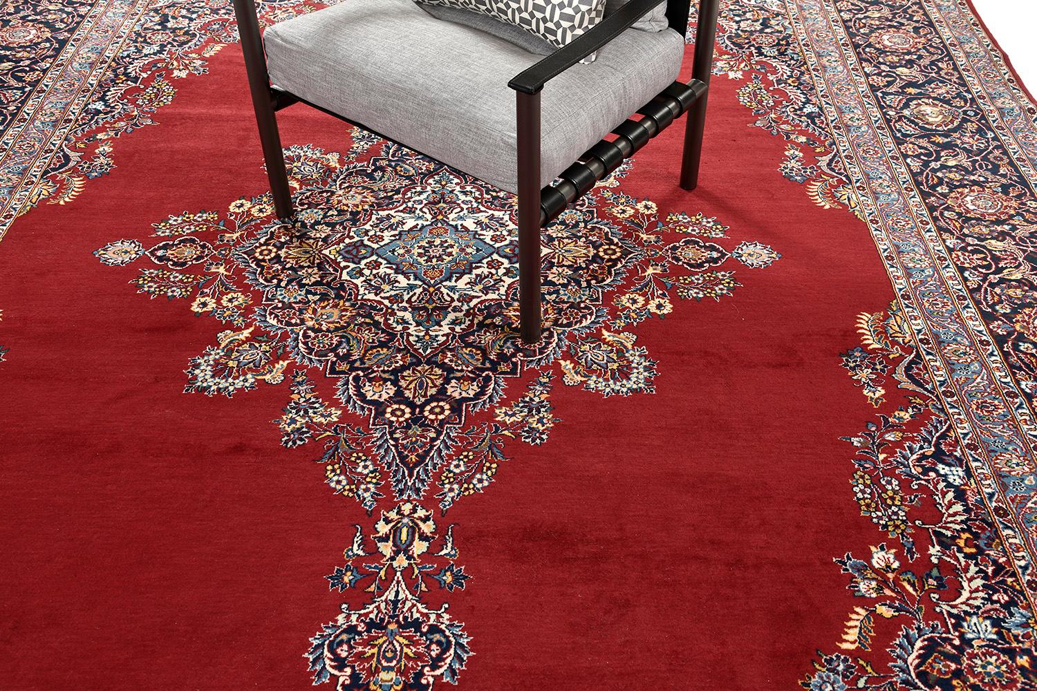 An impressive creation of Kashan rug that features a penny-worth impact from its every design. At its core, majestically presents a detailed diamond-shaped floral theme, motifs, and leafy scrolls. An effortless combination of various symmetrical