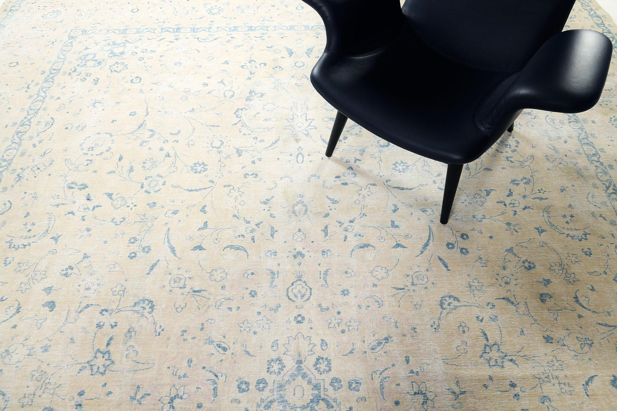A captivating Vintage Persian Kerman rug that is a perfect addition to your dream interiors. Featuring the stunning shades of ecru and cobalt blue, this mesmerizing rug boasts its lush dainty florettes strewn gracefully along the abrashed field. A