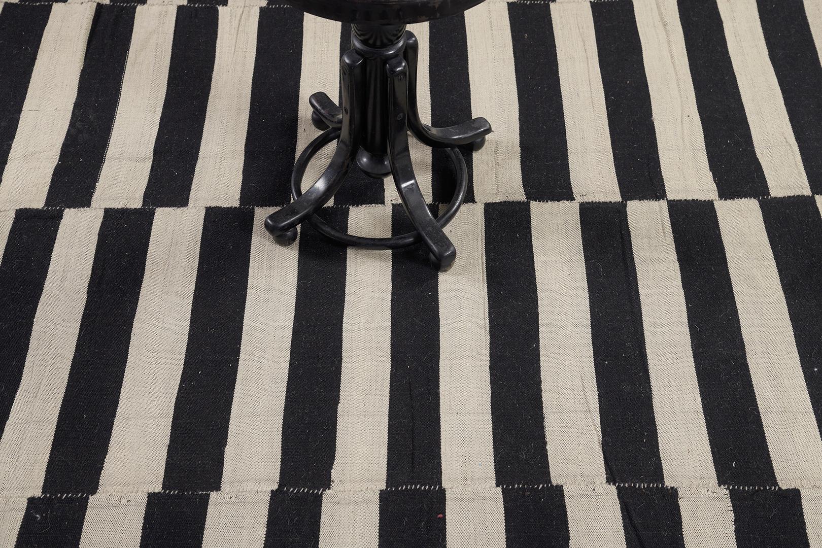 A stunning vintage Persian Kilim flatweave banded with black and neutral palette stripes. The varying degrees of stripes create a modest yet fascinating design for an extensive variety of interiors. A stylishly beautiful masterpiece that your guest