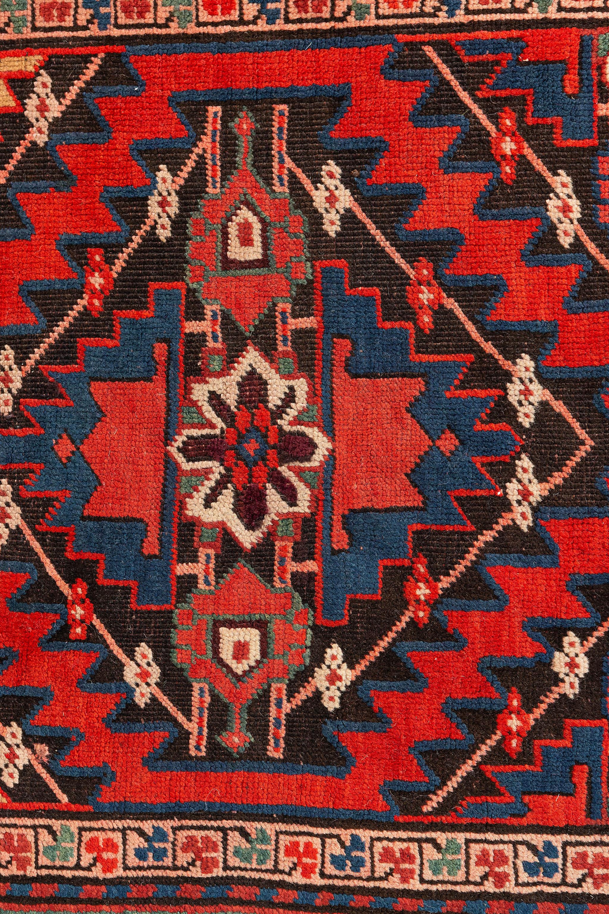 Dieser russische Kazak-Runenr-Teppich im Vintage-Stil weist fünf rote achteckige Guls auf, die mit königsblauen Riegelhaken umrandet sind. Jedes Gul ist mit einem achtzackigen Stern der Weisheit auf einem beigen Hintergrund gefüllt, der von