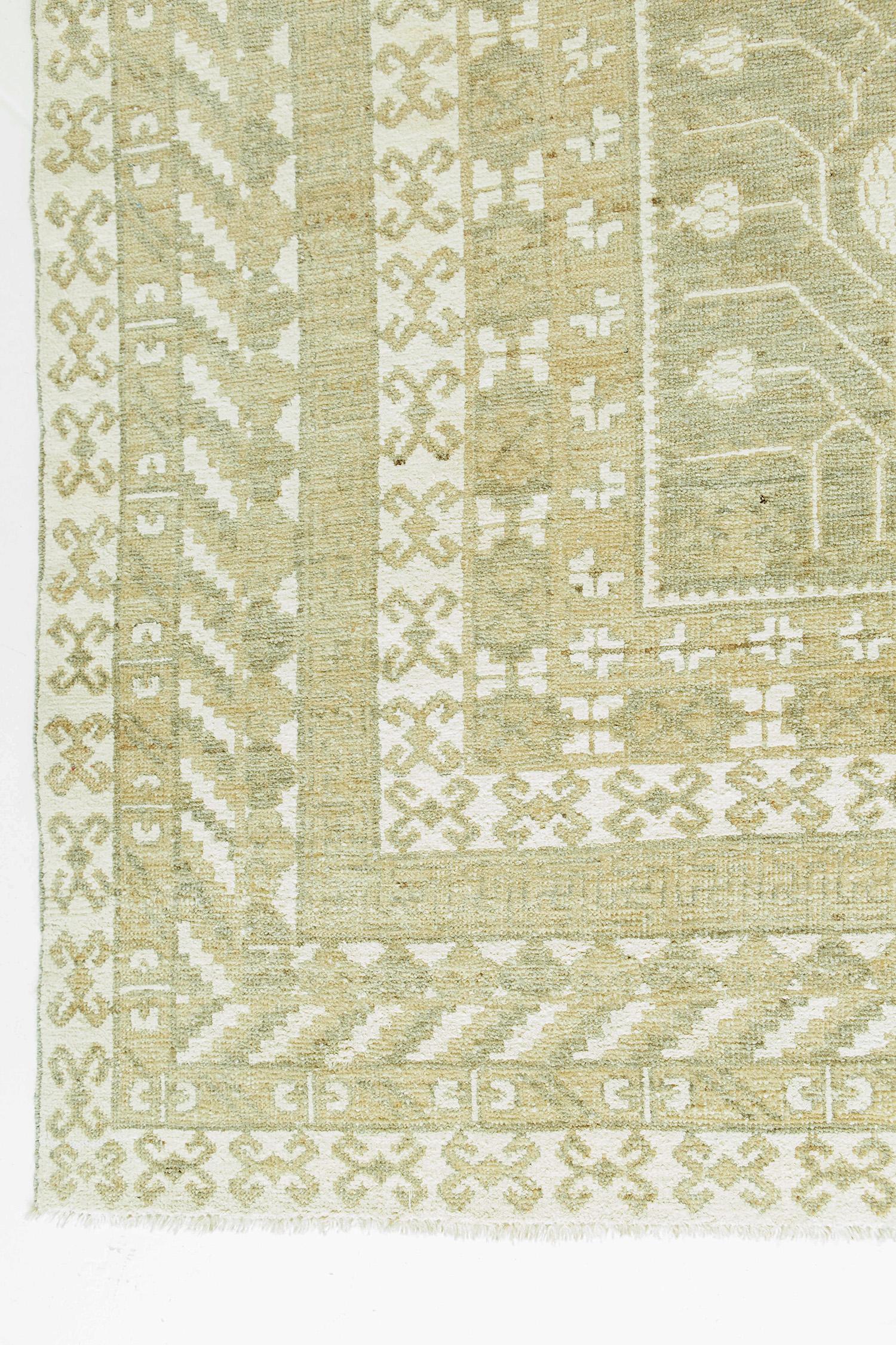 A beautiful traditional Khotan recreation featuring tribal pomegranate motifs and floral scrolls. The fascinating designs are depicted in ivory with a rich taupe background. The geometric patterns of Khotan rugs exude both sophistication and