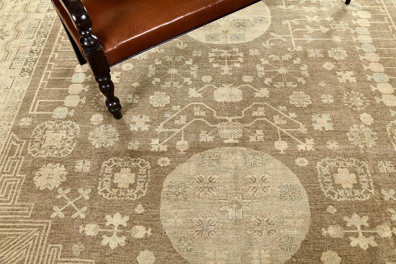 A breathtaking Khotan revival piece that highlights a field of botanical elements comprised of pomegranate and stylized florals. This magnificent rug exudes cozy and dainty elegance featuring the fascinating muted tones of camel, taupe and dusty