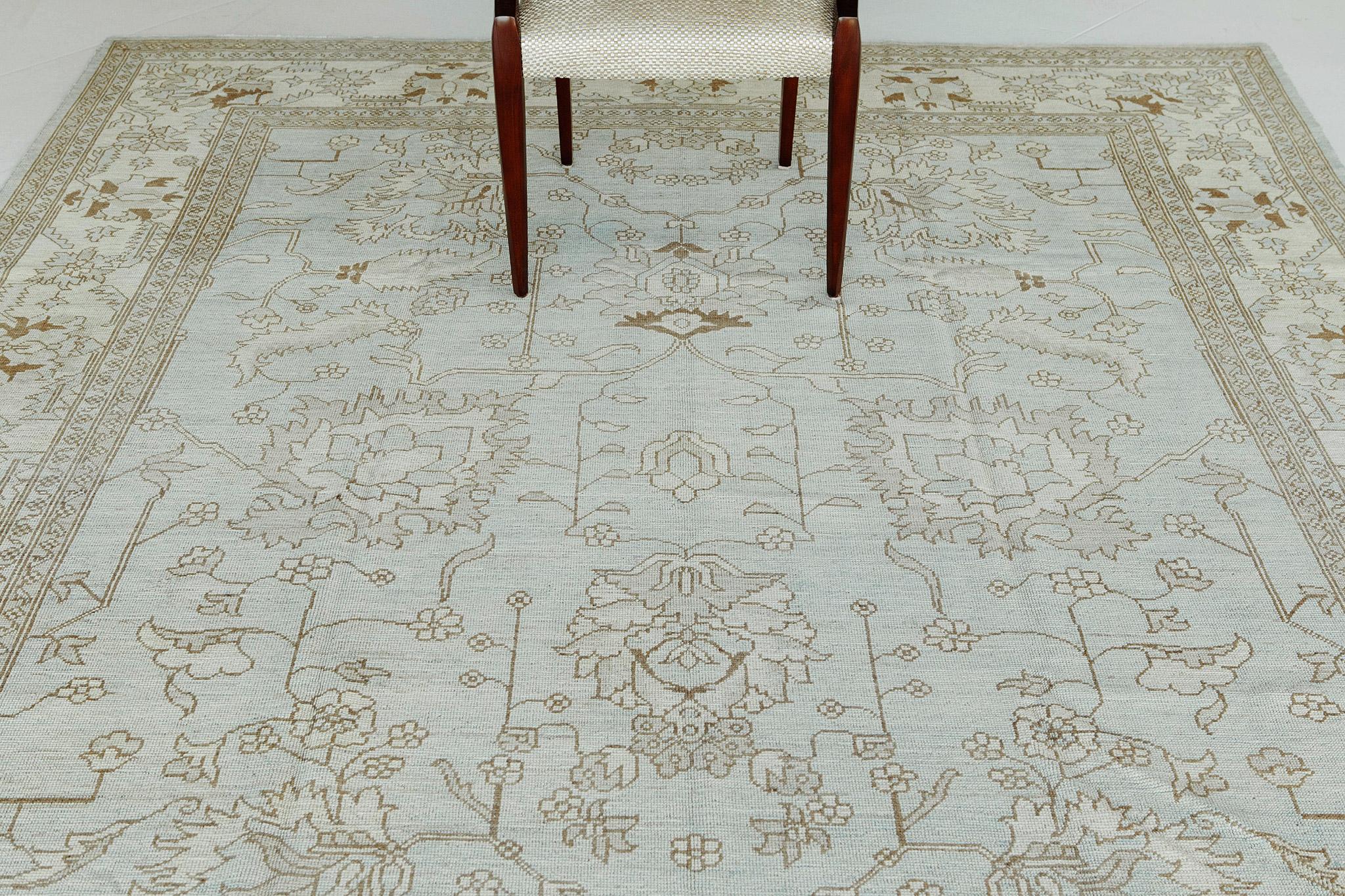 A vintage style Oushak revivial with a beautiful blue field and detailed surrounding borders. This recreation encompasses a tasteful geometric design that is both lively and luxurious. This rug is suitable for both traditional and modern interiors.