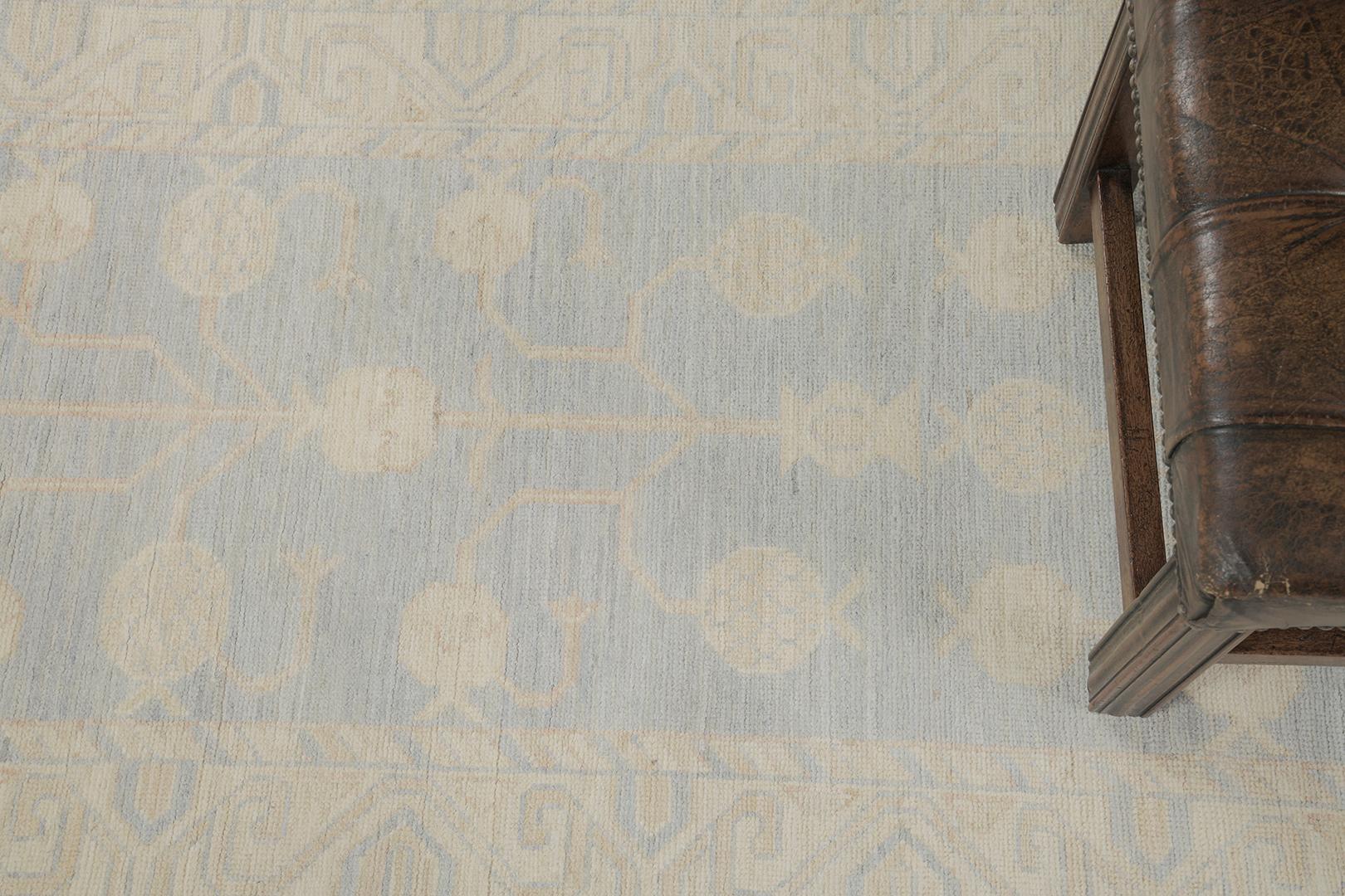 Dieser atemberaubende Khotan Designteppich eignet sich ideal als Bodenbelag. Ein elegantes Granatapfel-Motiv wird durch verstreute stilisierte Elemente makellos ausgefüllt. Von den geometrisch gemusterten Bordüren bis hin zu den gedämpften, kühlen