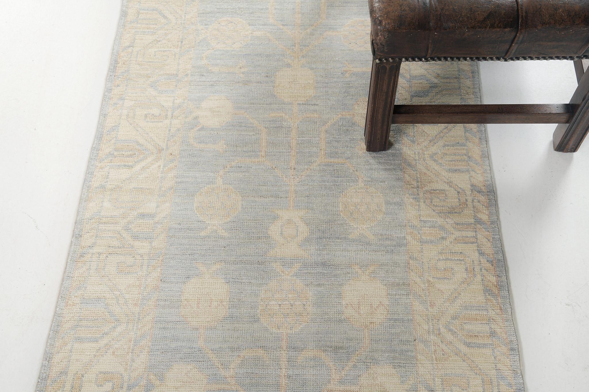 Dieser beeindruckende Khotan Designteppich eignet sich ideal als Bodenbelag. Ein majestätisches Granatapfel-Motiv wird durch verstreute stilisierte Elemente einwandfrei ausgefüllt. Von den geometrisch gemusterten Bordüren bis hin zu den gedämpften,