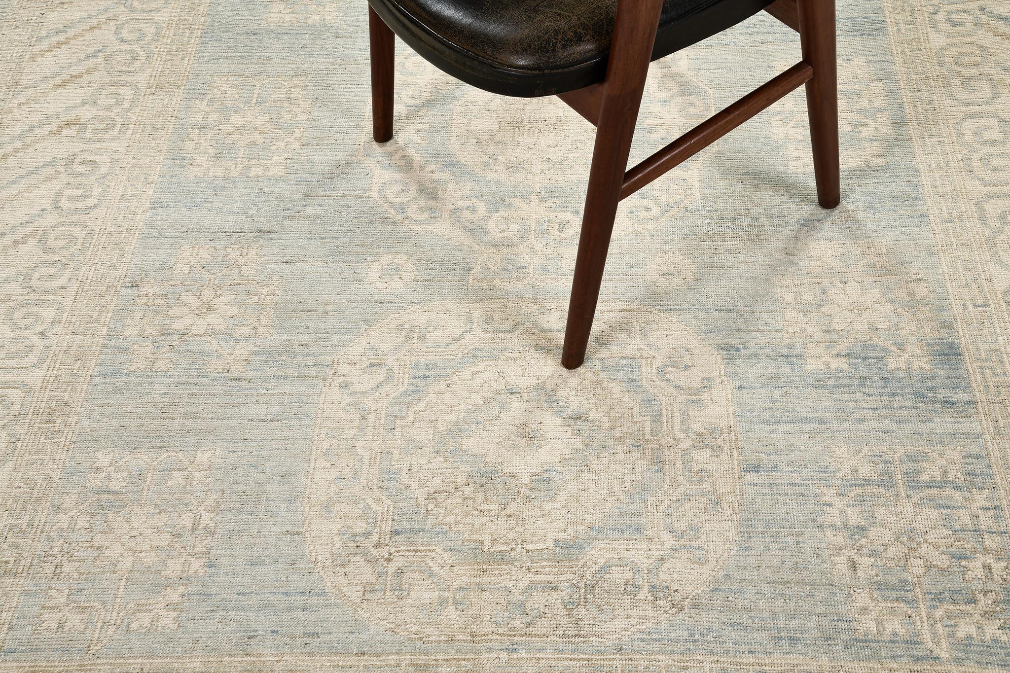 A spectacular revival of Khotan design rug in the soothing muted tones of sky blue, sand and gold. This sophisticated rug features three ornately designed medallions surrounded by blooming florid elements in a tranquil abrashed field. With its