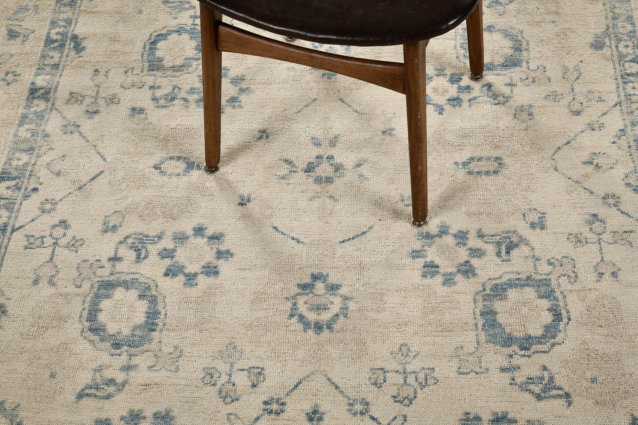 Une reprise élégante d'un tapis en laine filée à la main de la Collection Sals du Khotan, éclairée par les points forts d'un contraste de bleu et de beige. Les symboles et les motifs sont alignés avec des espaces au centre remplis de vignes et