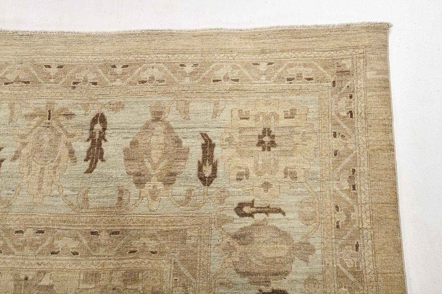 A breathtaking muted revival of Sultanabad rug that exudes dainty elegance featuring curved leaves and awe-inspiring floral composition of blooming palmettes strewn gracefully along the pale beige field. It is enclosed by inner and outer floral