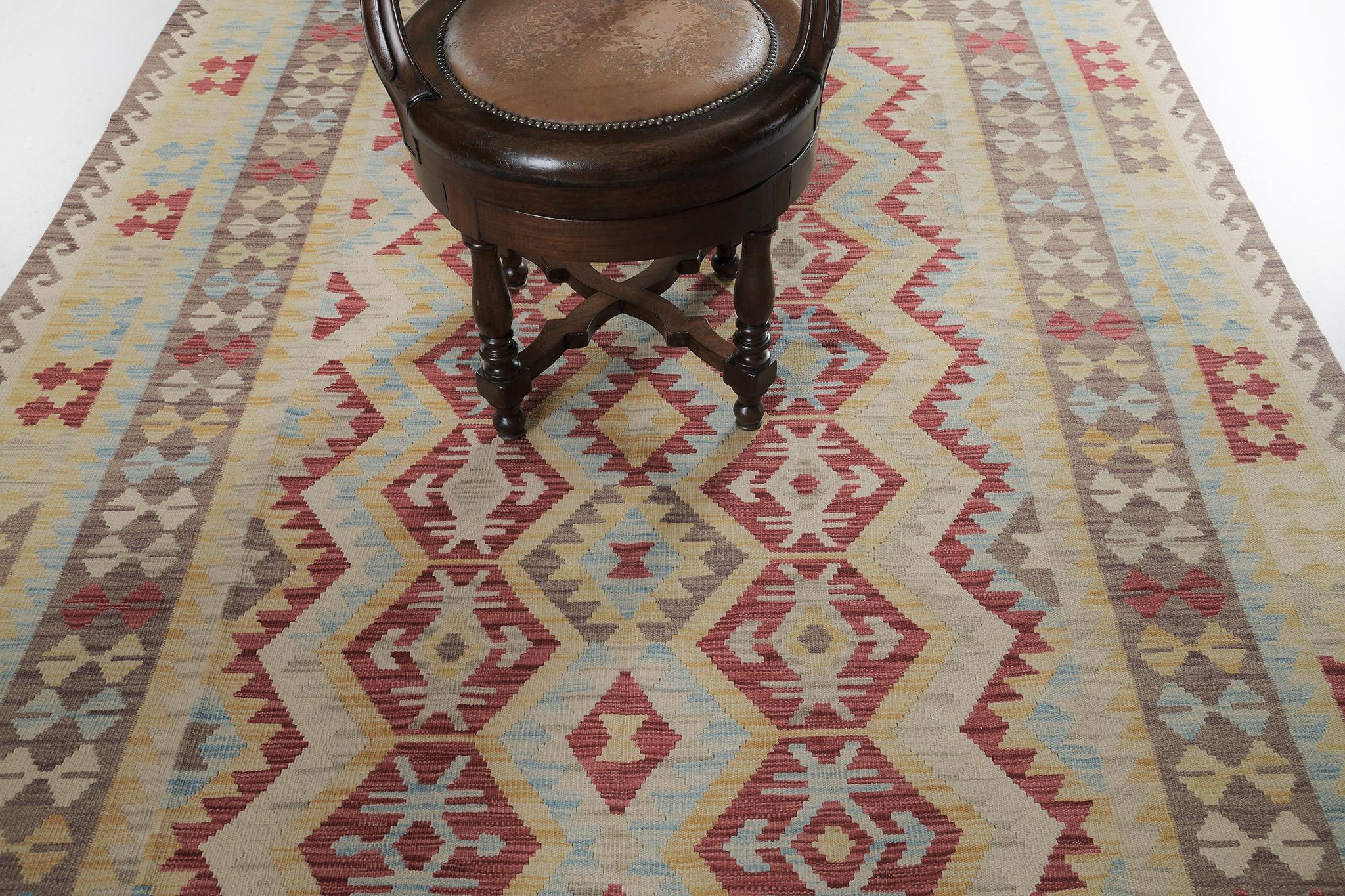 An outstanding wool flatweave kilim in vintage style has flexed its versatility and mischievousness. Stylized motifs and geometrical designs in variegated tones of ash gray and cream field and combinations of yellow, red, blue, ivory, and green