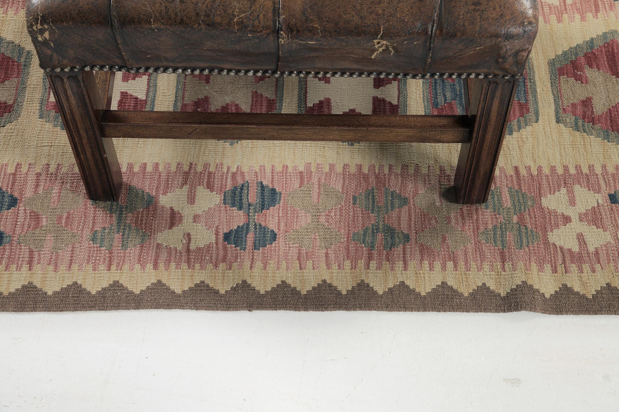 Dieser hervorragende Flachgewebe-Kilim zeichnet sich durch eine beeindruckende und lebendige Komposition aus und zeigt einige der Feinheiten der traditionellen Weberei. Eine schillernde Farbpalette in neutralen Tönen mit einem roten Akzent veredelt