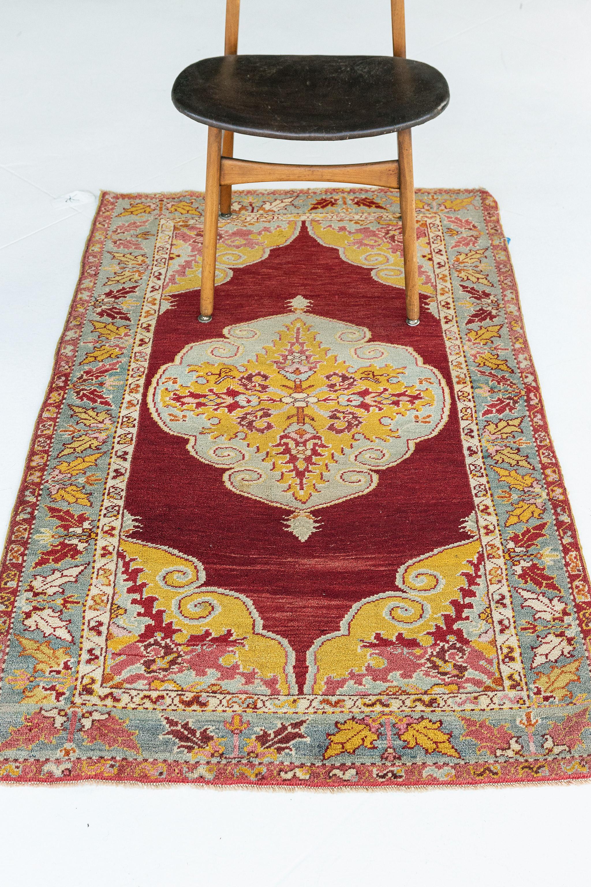 Questo tappeto vintage turco anatolico è caratterizzato da una composizione lussuosa che raffigura antichi motivi anatolici. Al centro della scena c'è un medaglione centrale a losanghe con motivi di iris e fiori stilizzati. Un bordo a meandro