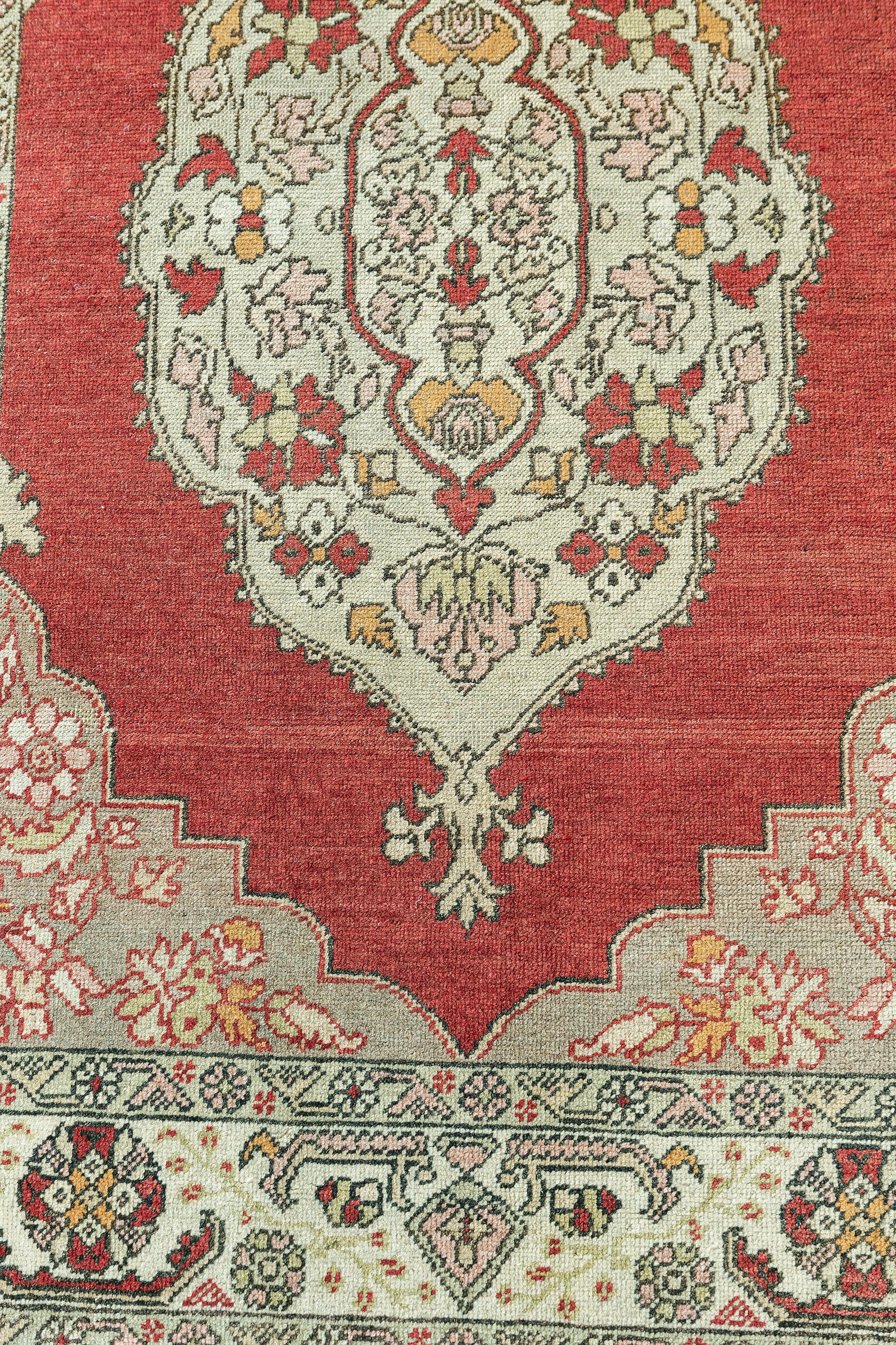 This Vintage Turkish Anatolian rug features a cusped central medallion flanked with stylized florals. The central medallion is surrounded by a botanical scene composed of rose, iris, blossoms and thin angular vines dancing rhythmically throughout