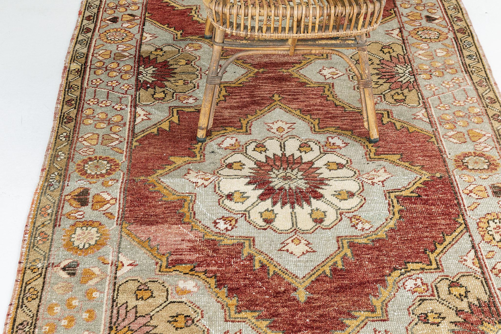 This Vintage Turkish Anatolian Runner features an all-over array of lozenge botanical medallions composed blossoms and stylized florals laying on the coral and terracotta field. A stylized botanical Meander border flanked with inner and outer flower