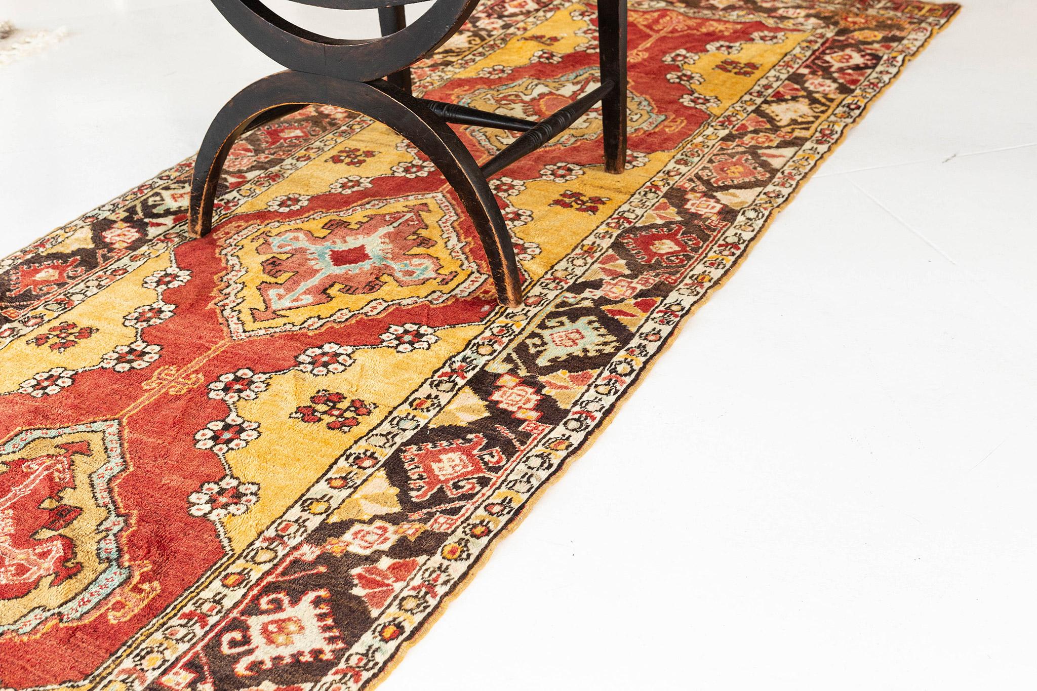 An exceptional vintage Turkish Anatolian Runner that will enhance your room through the elegant bursts of its vibrant colours. The contemporary feels given by this exquisite rug features the stunning colour palette of gold and terracota in an