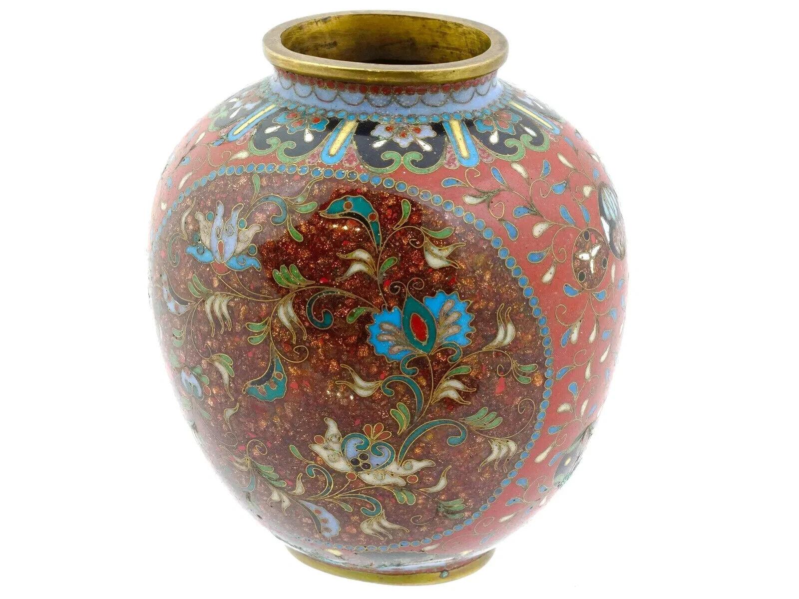 A Japanese enamel over copper vase. The sphere shaped vase is enameled with polychrome medallions representing floral and butterfly designs surrounded by floral, foliage and foliate scroll ornaments made in the Cloisonne technique. The base and the