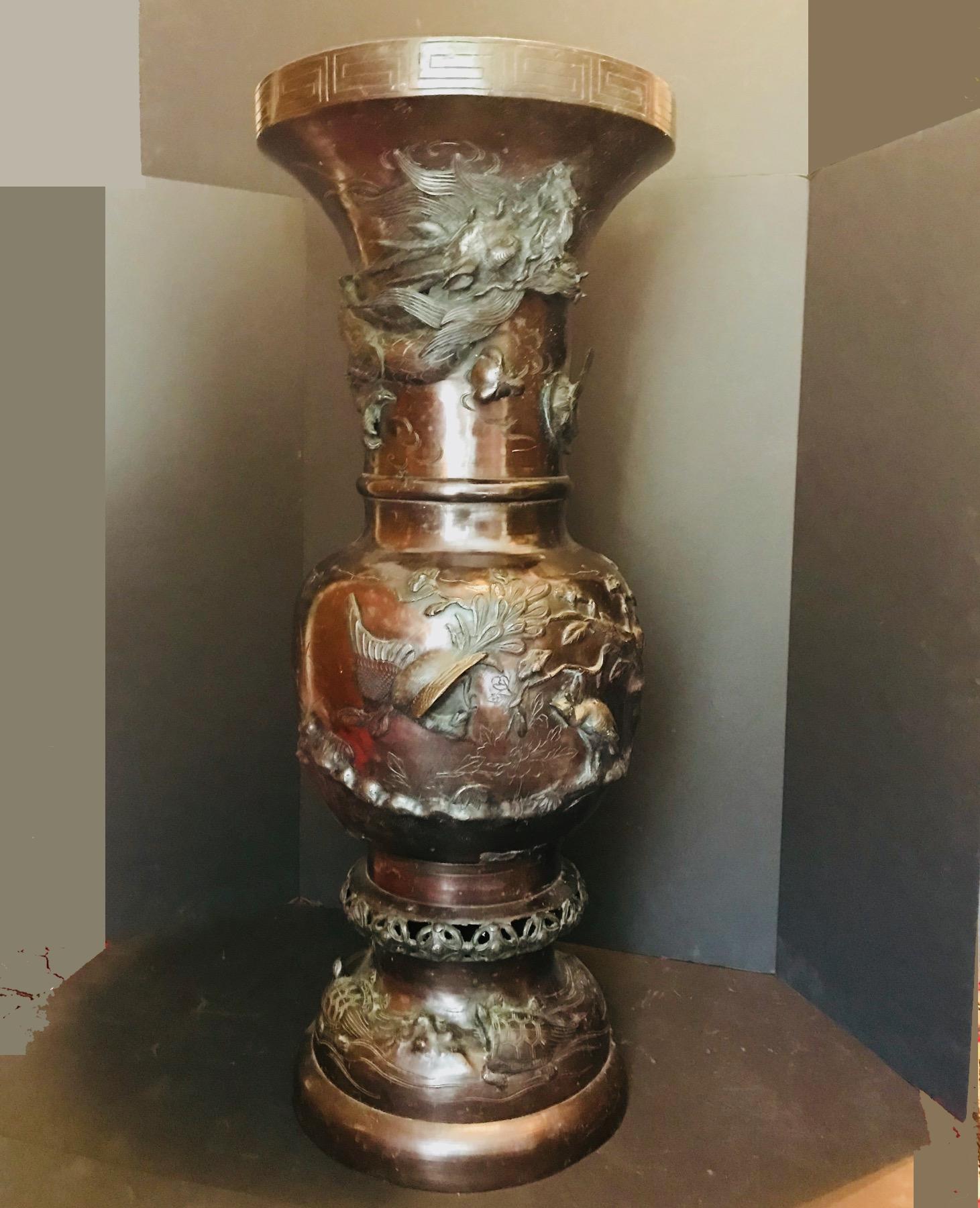 This is a stunning Japanese bronze urn or vase with a highly raised and heavy casted design throughout with figural creatures, cranes and turtles. The fine details are magnificent. This piece is in two sections and it has a rich brown bronze patina.