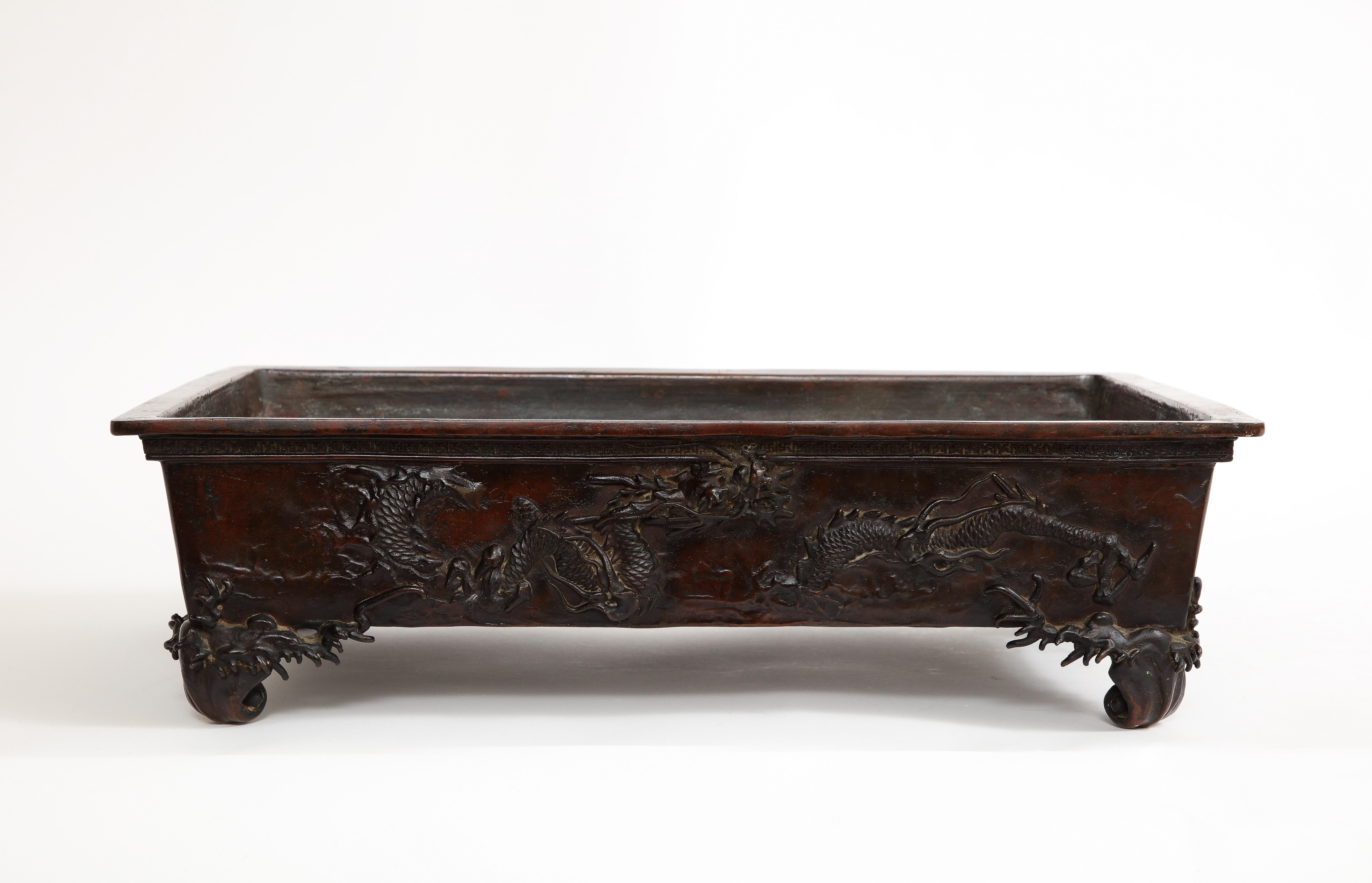 Cuenco de bronce para centro de mesa/planta de bonsái del periodo Meiji, 1890

Este centro de mesa o bonsái de bronce del periodo Meiji tiene forma rectangular, borde ancho y plano e interior profundo. El exterior está adornado con un relieve que