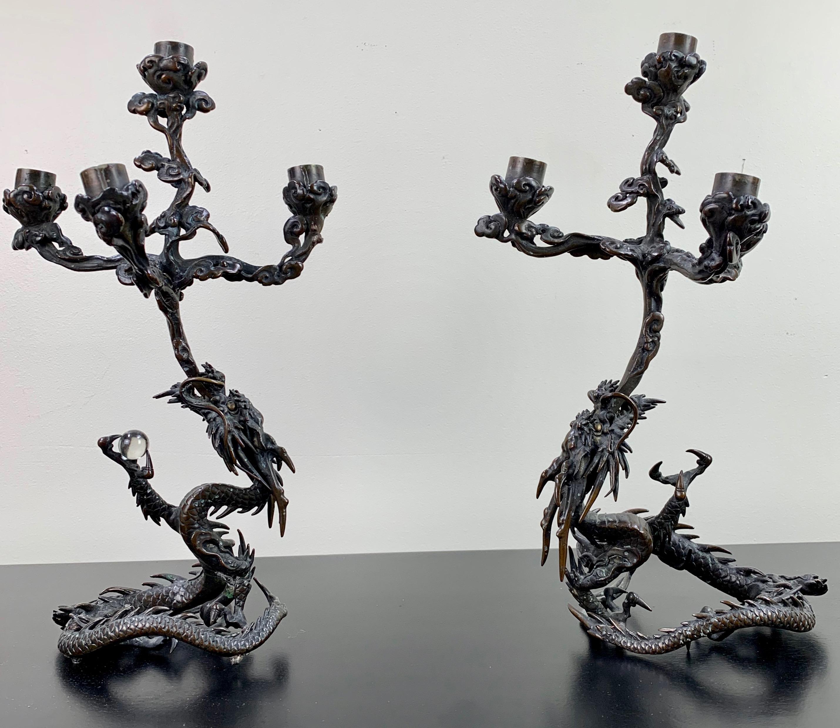 In two separate pieces, these bronze whimsical dragons hold a four arm candleholder in their mouths and a crystal ball in their claws.
