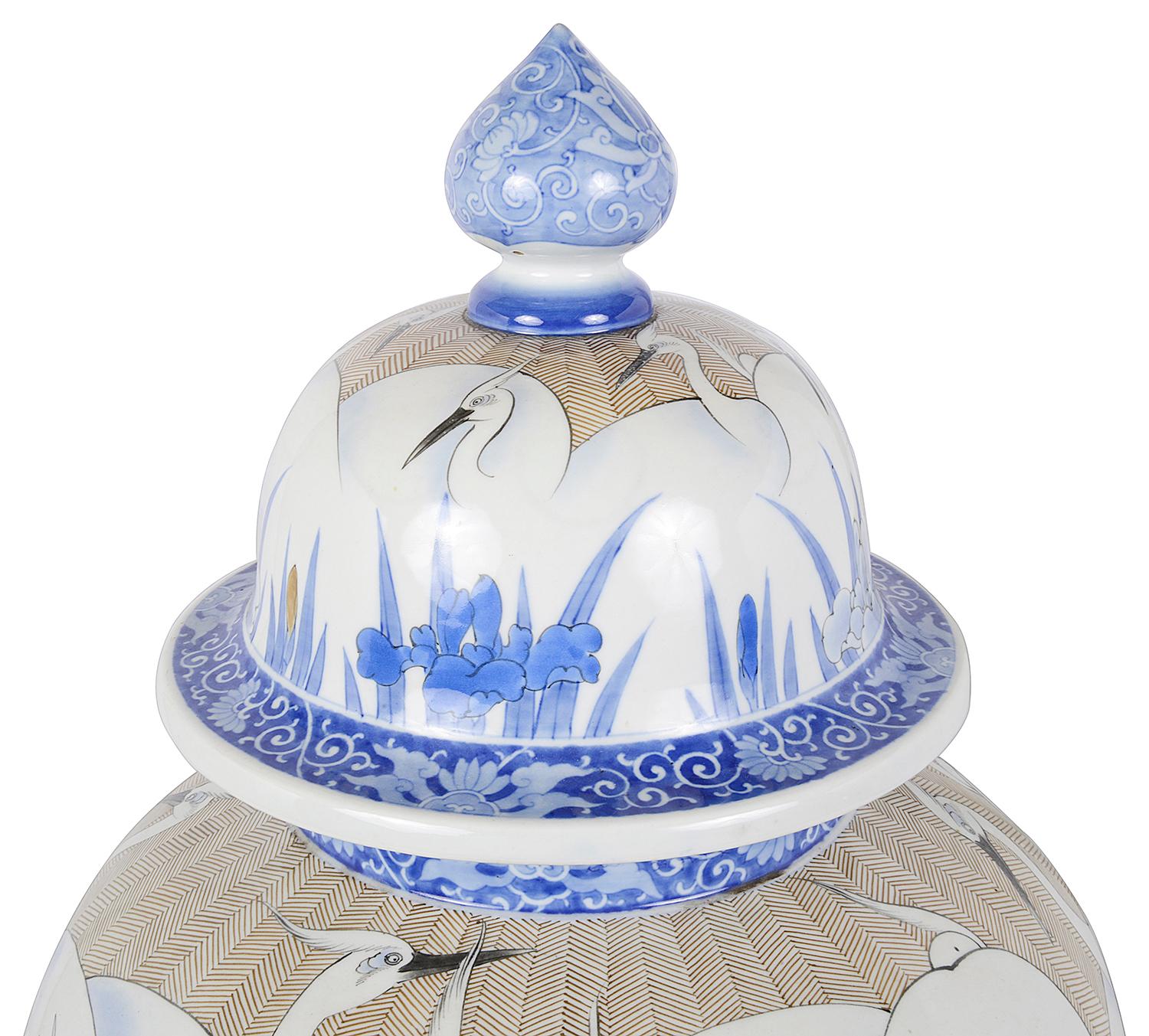 Vaso con coperchio in porcellana giapponese Fukagawa del periodo Meiji (1868-1912), dipinto a mano e di ottima qualità. Raffigura gru esotiche tra canne e gigli, con bordi di fogliame e motivi classici a scorrimento.